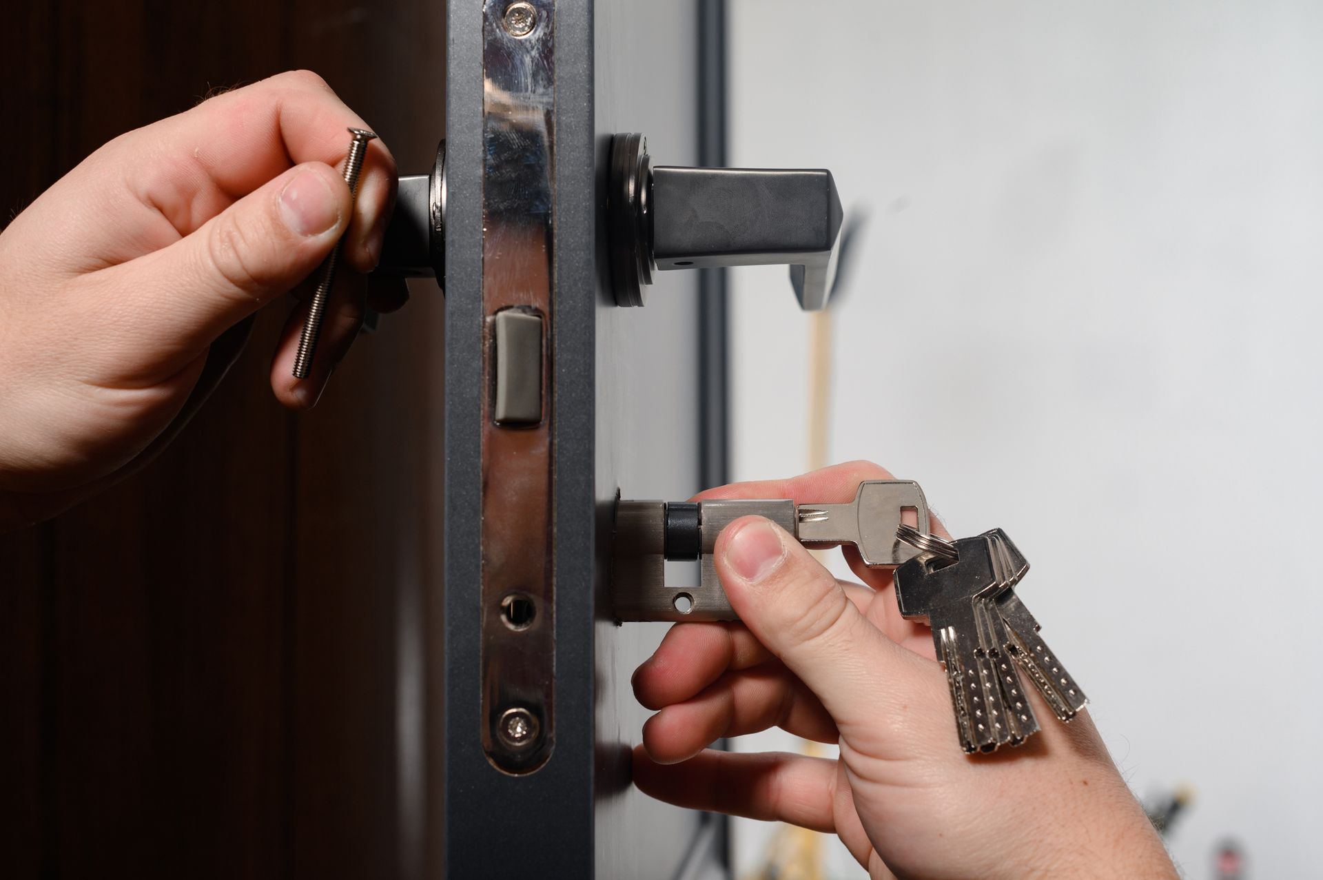 Hands Insert a Key Into a Door Lock While Holding the Latch Bolt Open — Terrace Locksmiths in Raymond Terrace, NSW