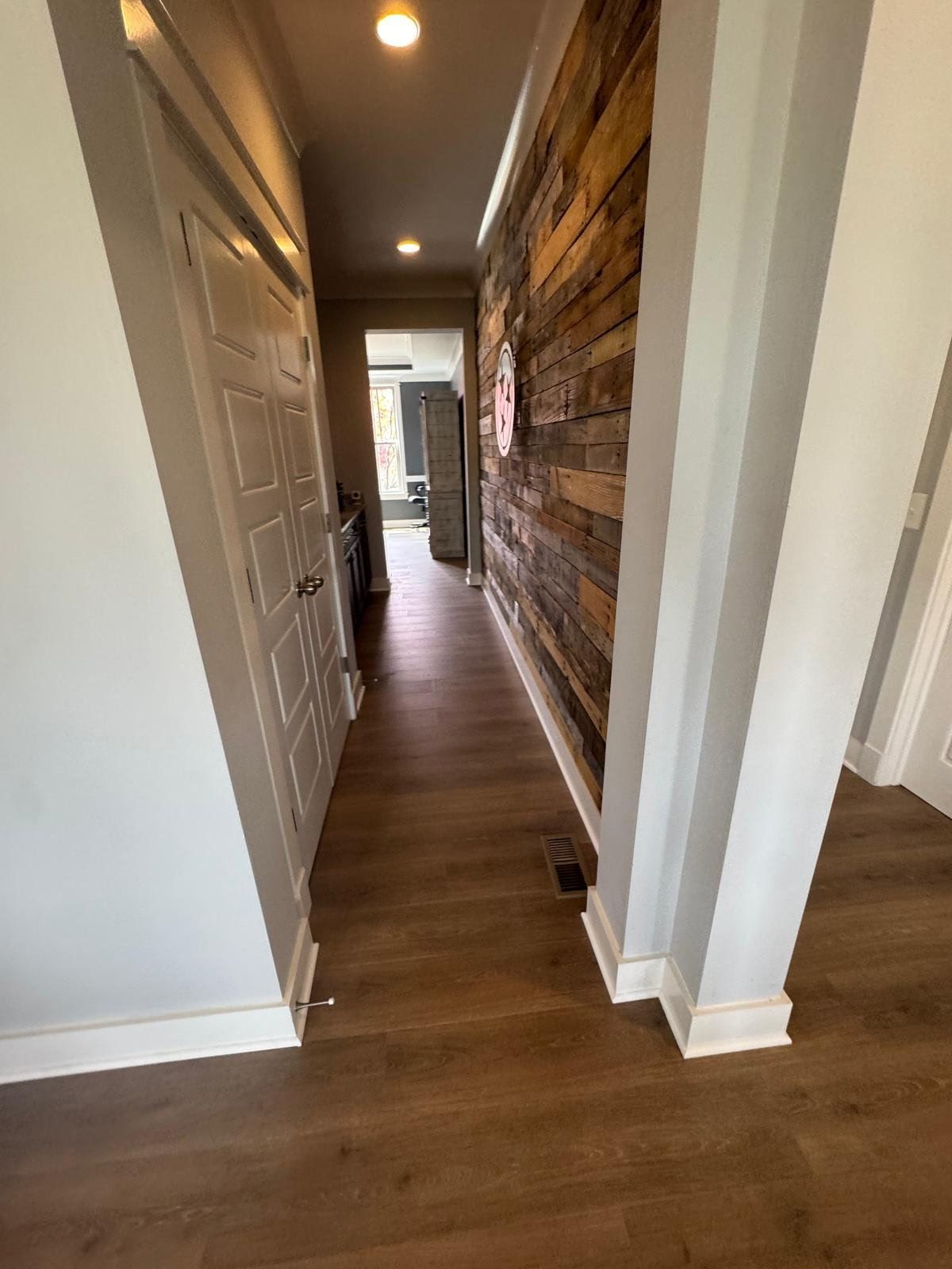 A hallway with hardwood floors and a wooden wall.