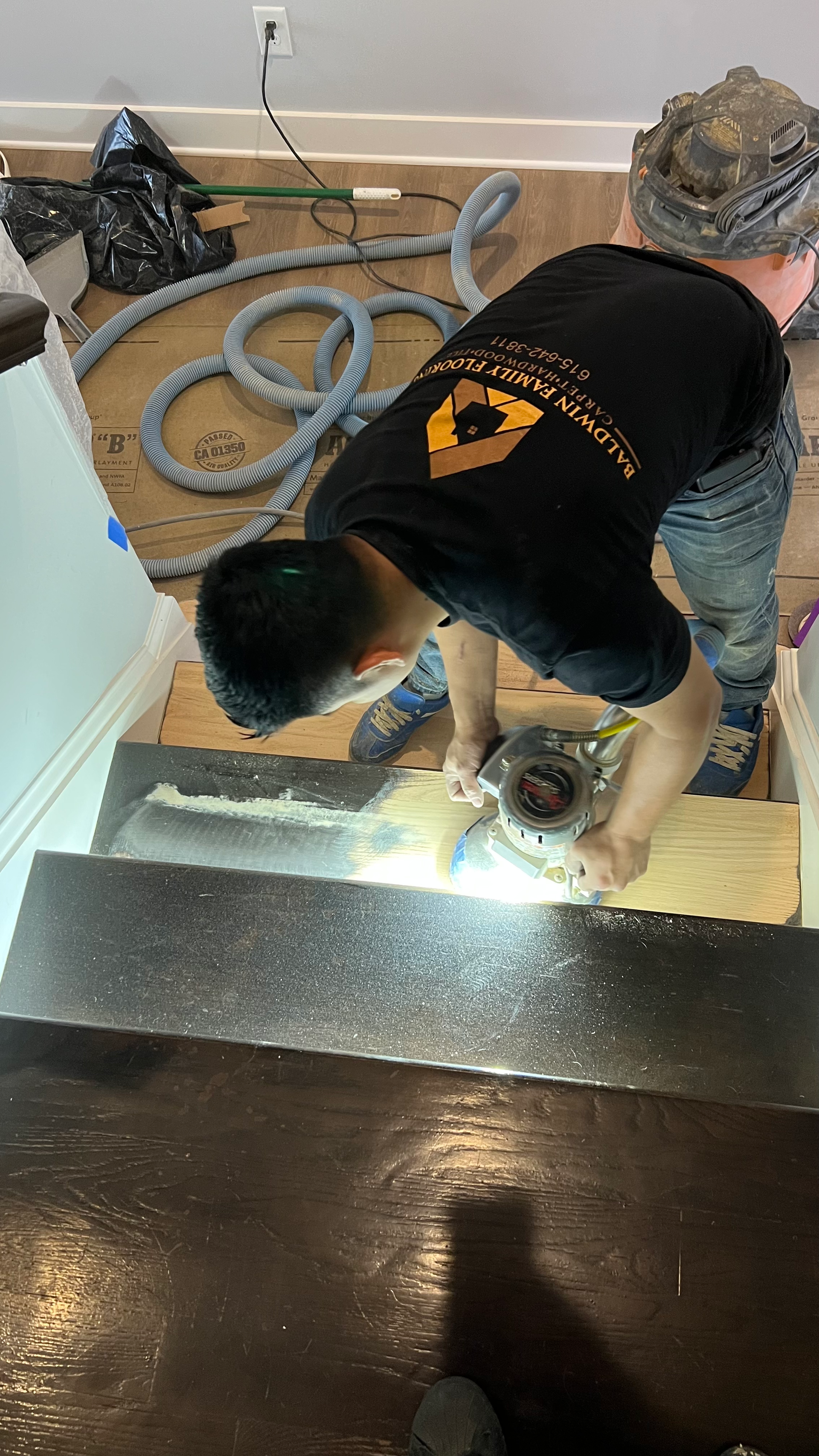 A man is working on a wooden floor in a room.