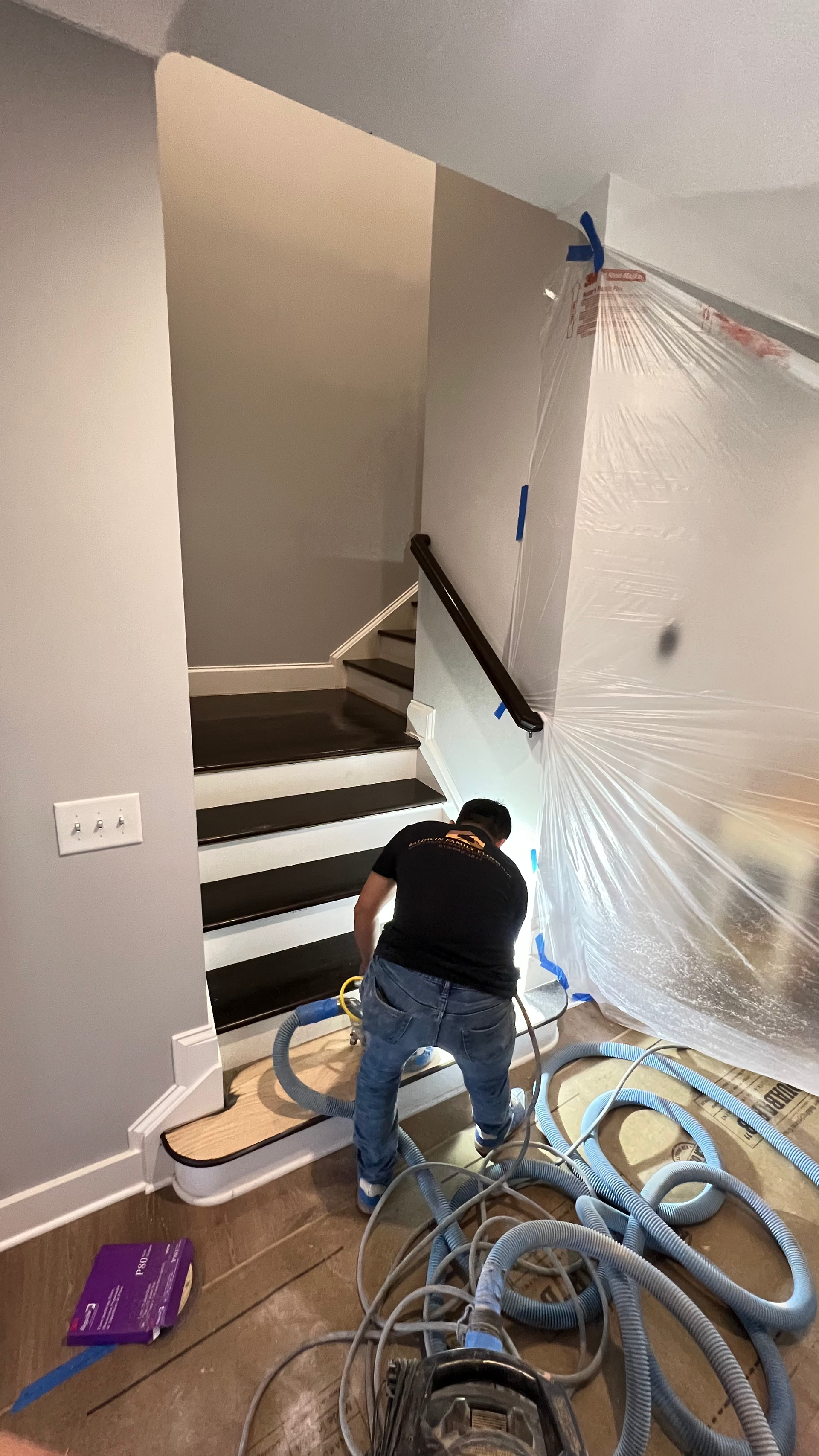 A man is cleaning a staircase with a vacuum cleaner.