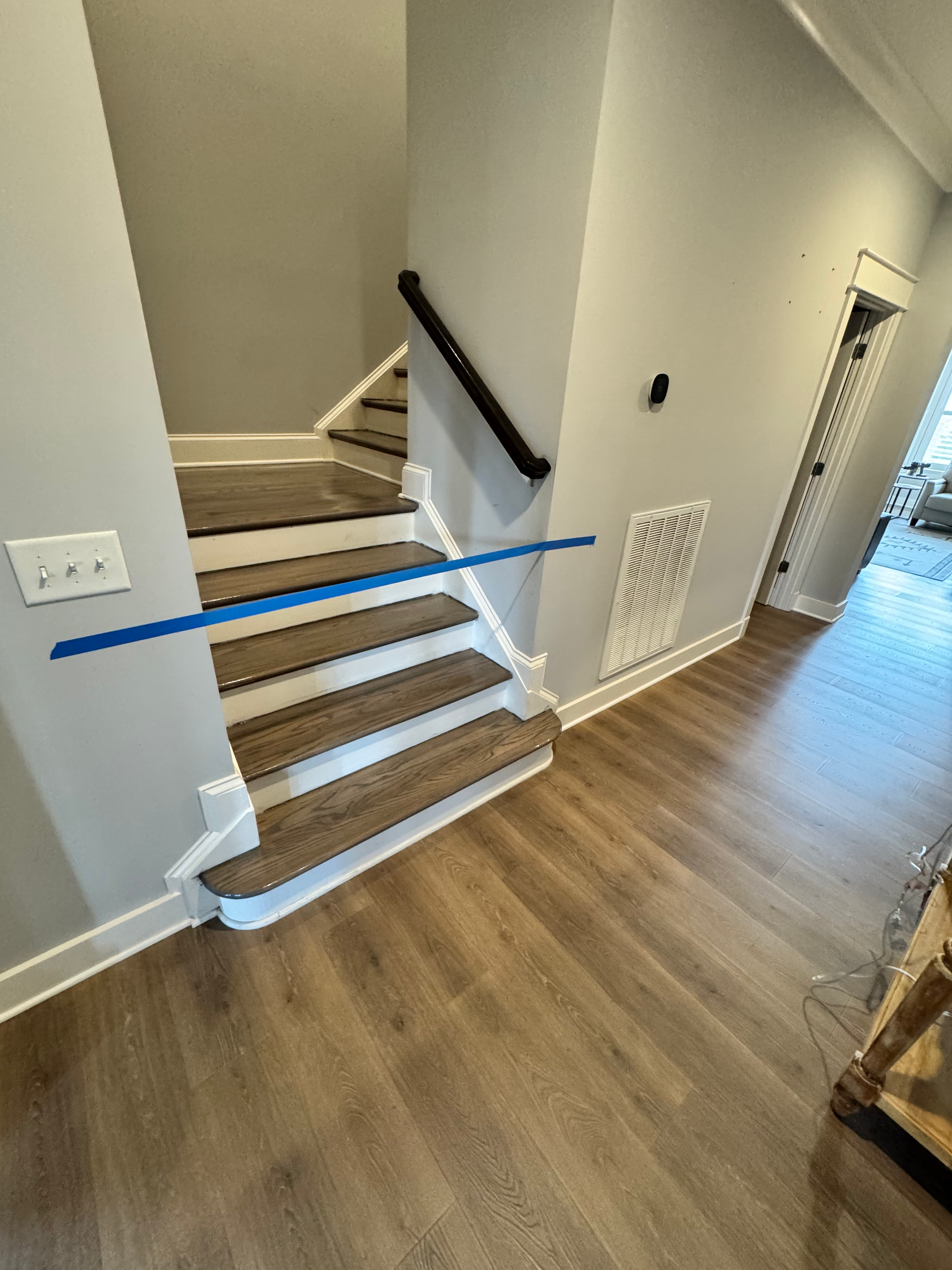 A staircase with wooden steps and a blue tape measure in a hallway.