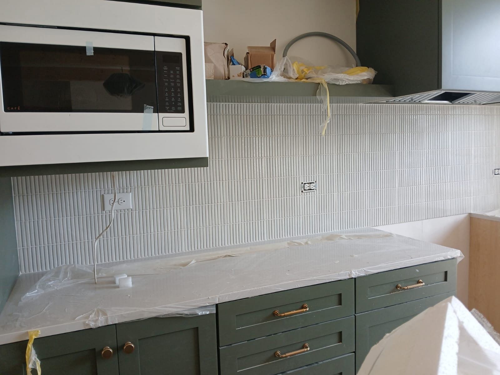 A kitchen with green cabinets and a white microwave.