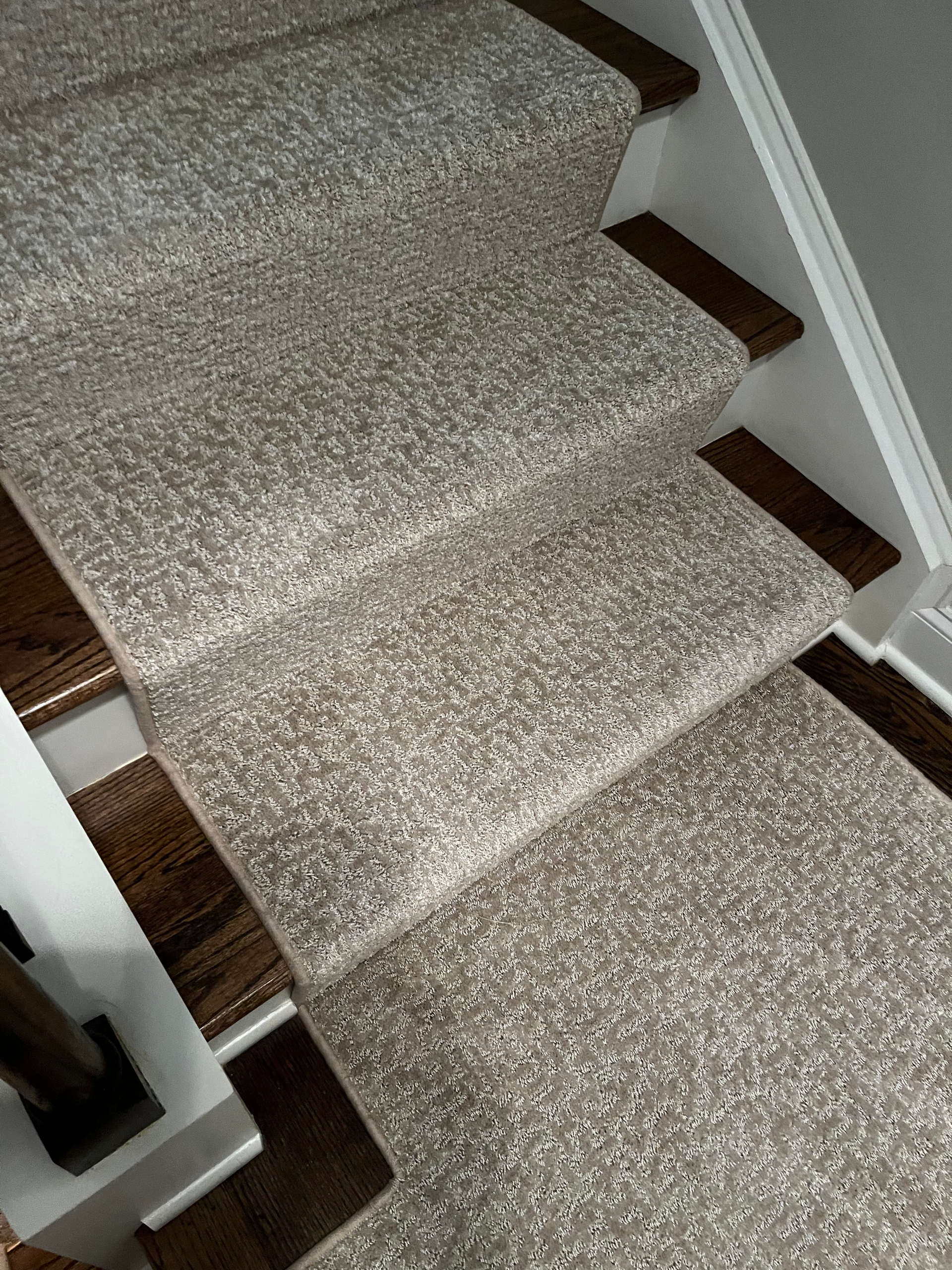 Carpeted stairs with wood trim and a white wall.