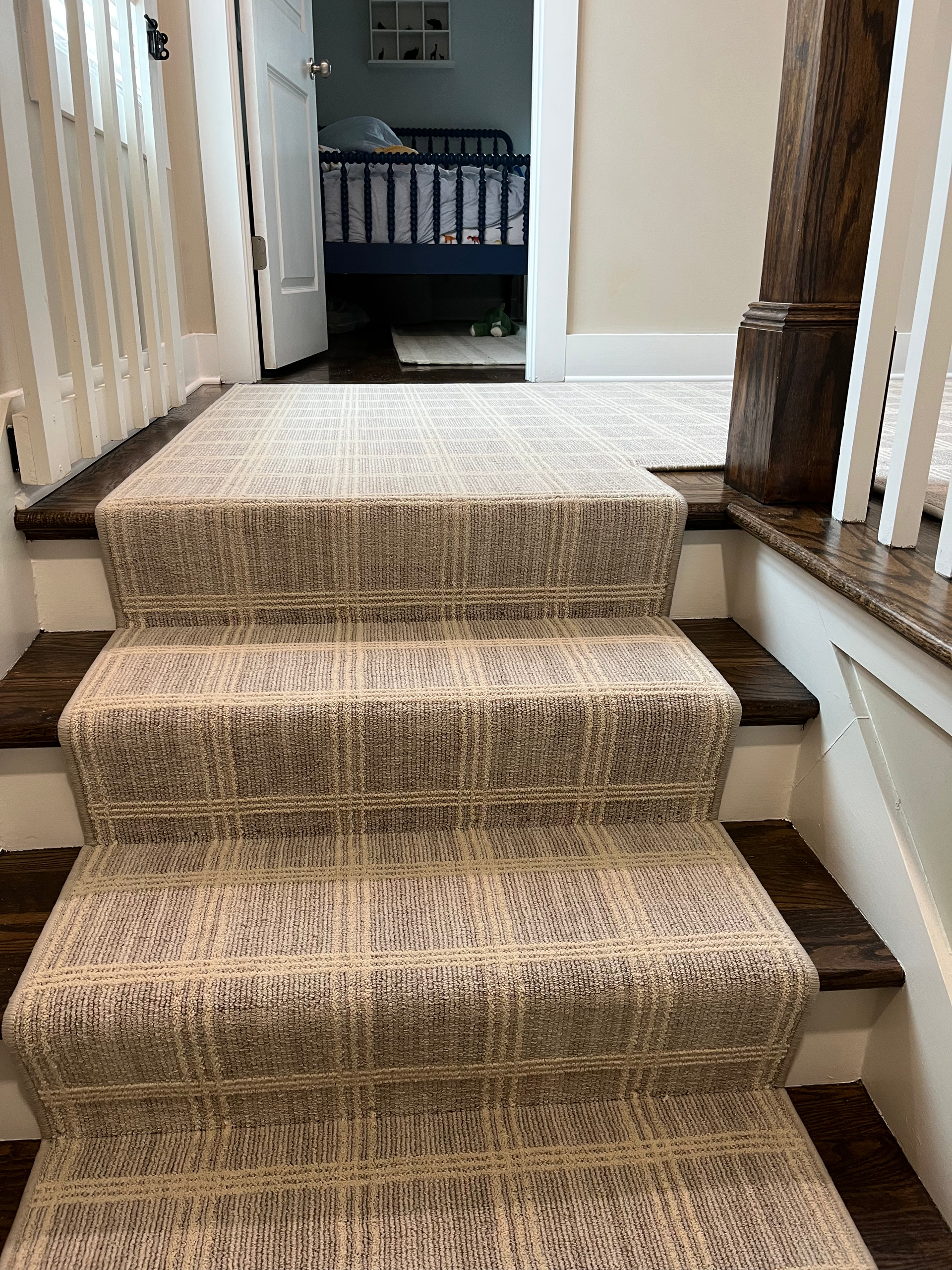 Staircase with patterned carpet, leading to a doorway and a glimpse of a crib.