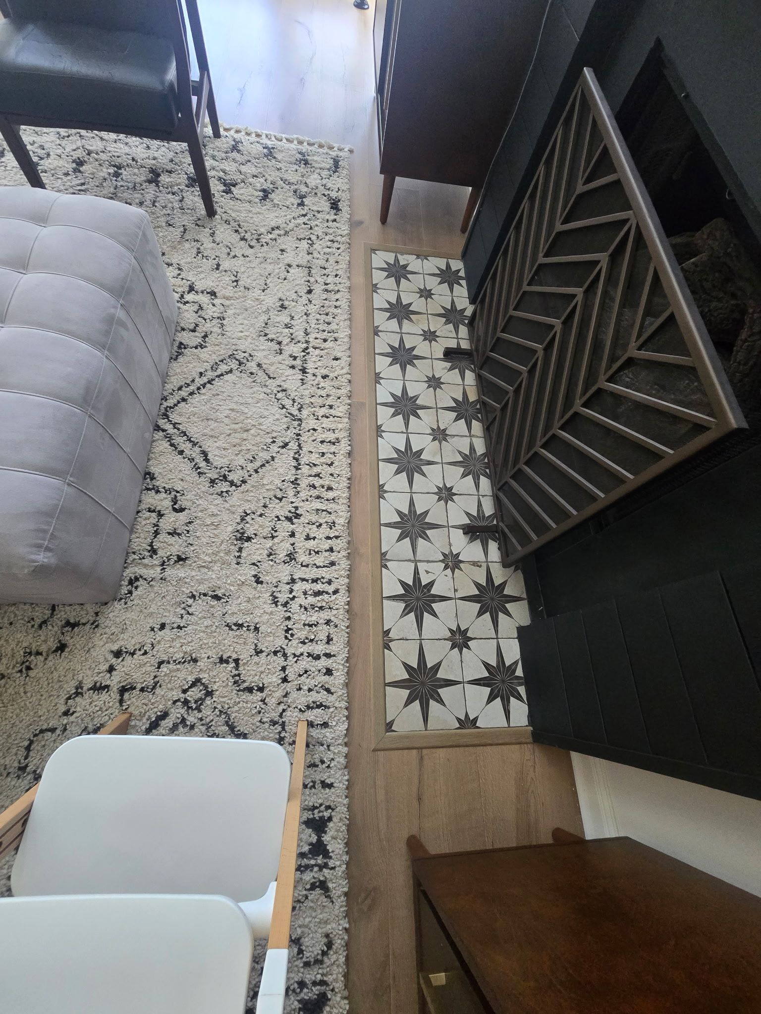 Overhead view of a living space with a patterned rug, tile, furniture and wooden floors.