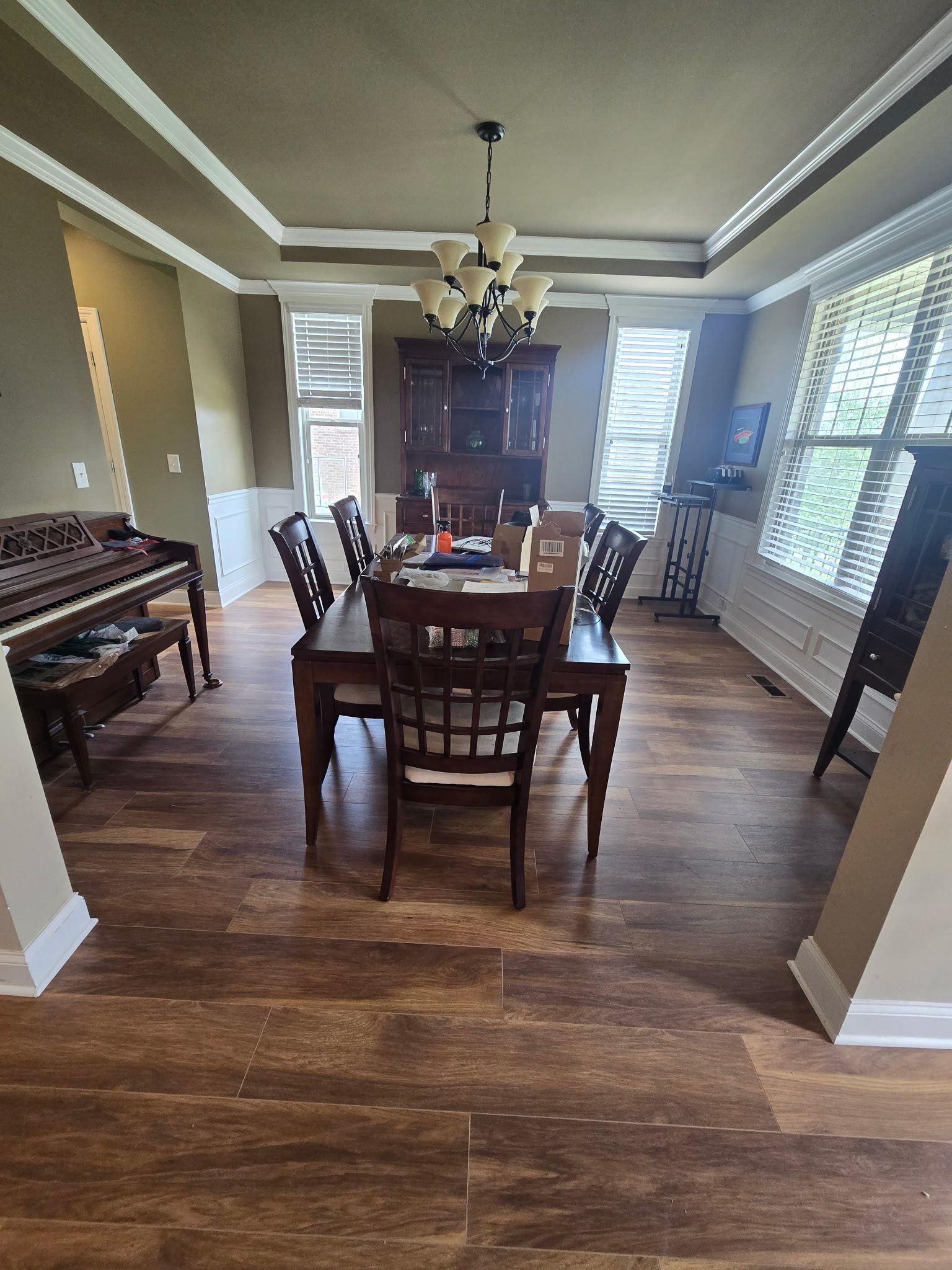 Dining room with wooden table, chairs, piano, and china cabinet; neutral colors.