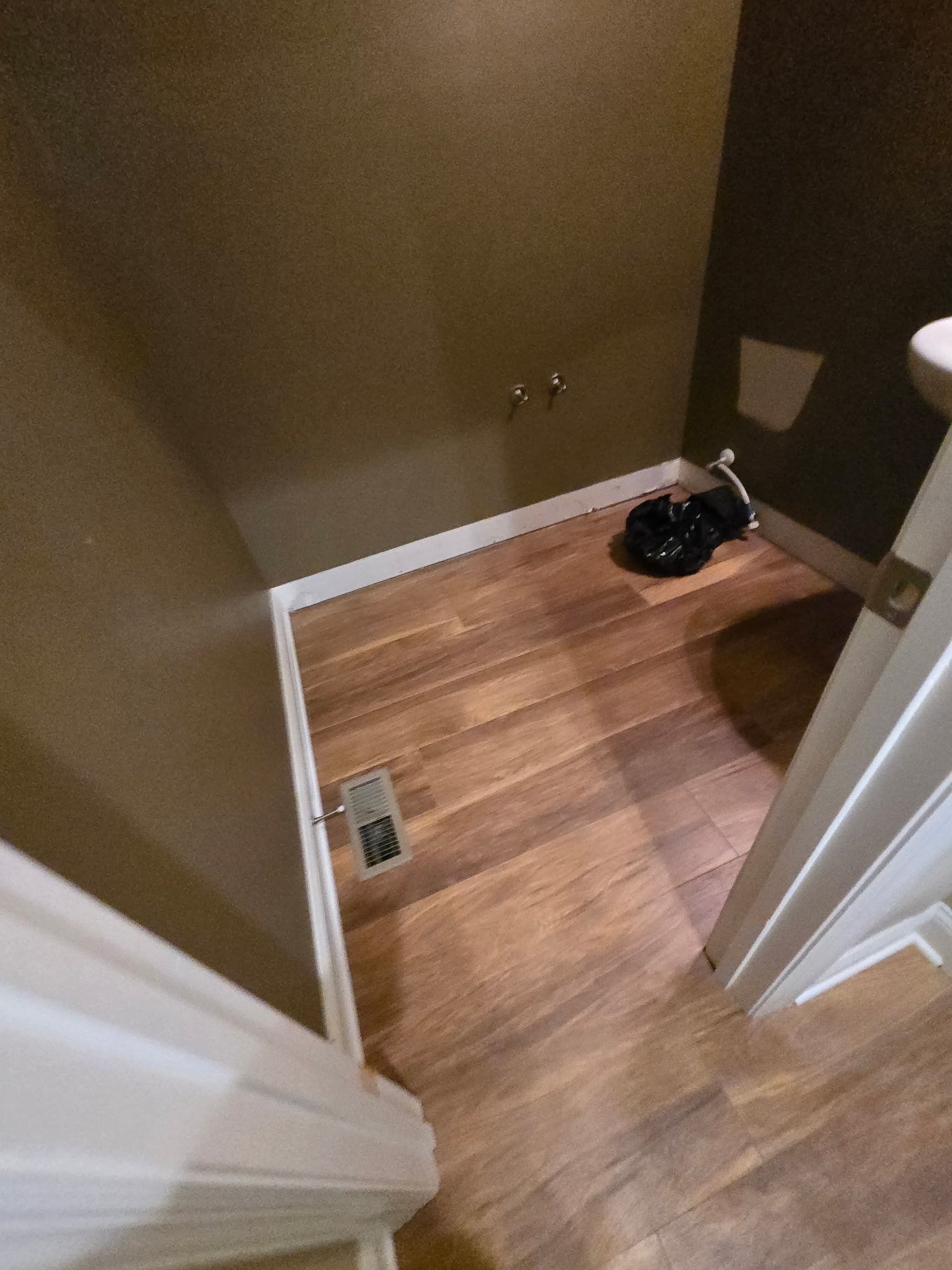 Small room with brown floors and walls, a white trim, and plumbing fixtures.
