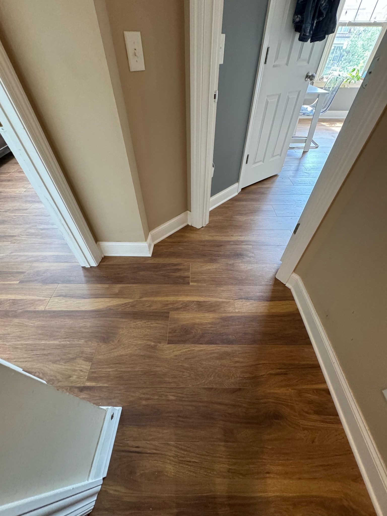Hallway with wood-look flooring, doorways, and neutral-colored walls.