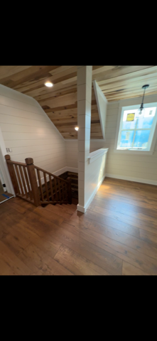 Interior view with a wooden staircase, wood floor, and white walls.