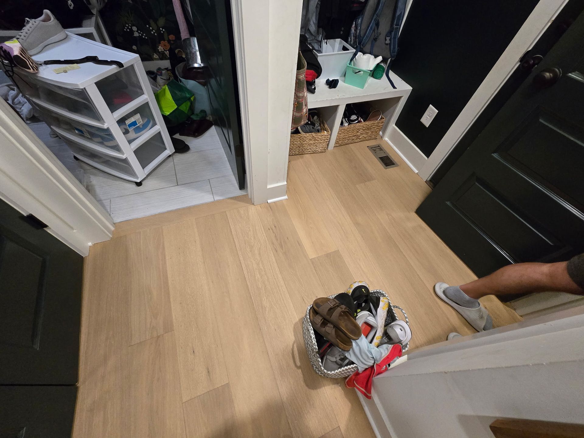 A cluttered hallway with light wood floors; storage units and an open closet are visible.