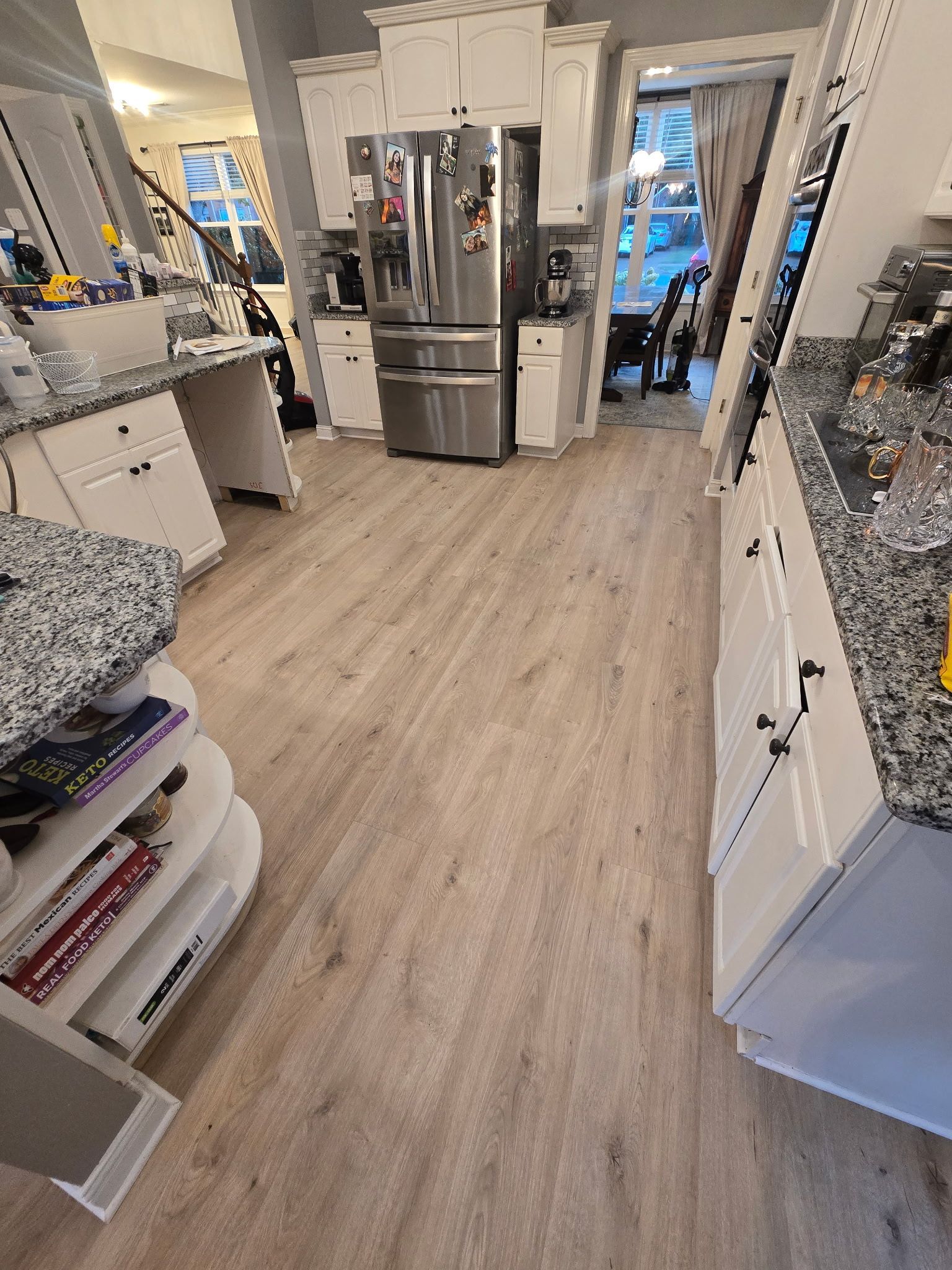 Kitchen with white cabinets, stainless steel refrigerator, and wood-look flooring.