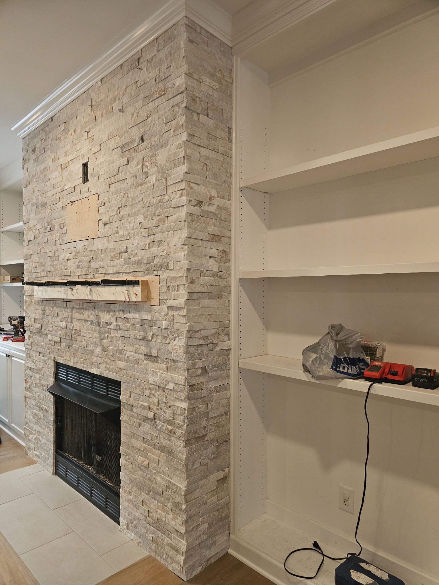 Fireplace with stone facade next to a white bookshelf.