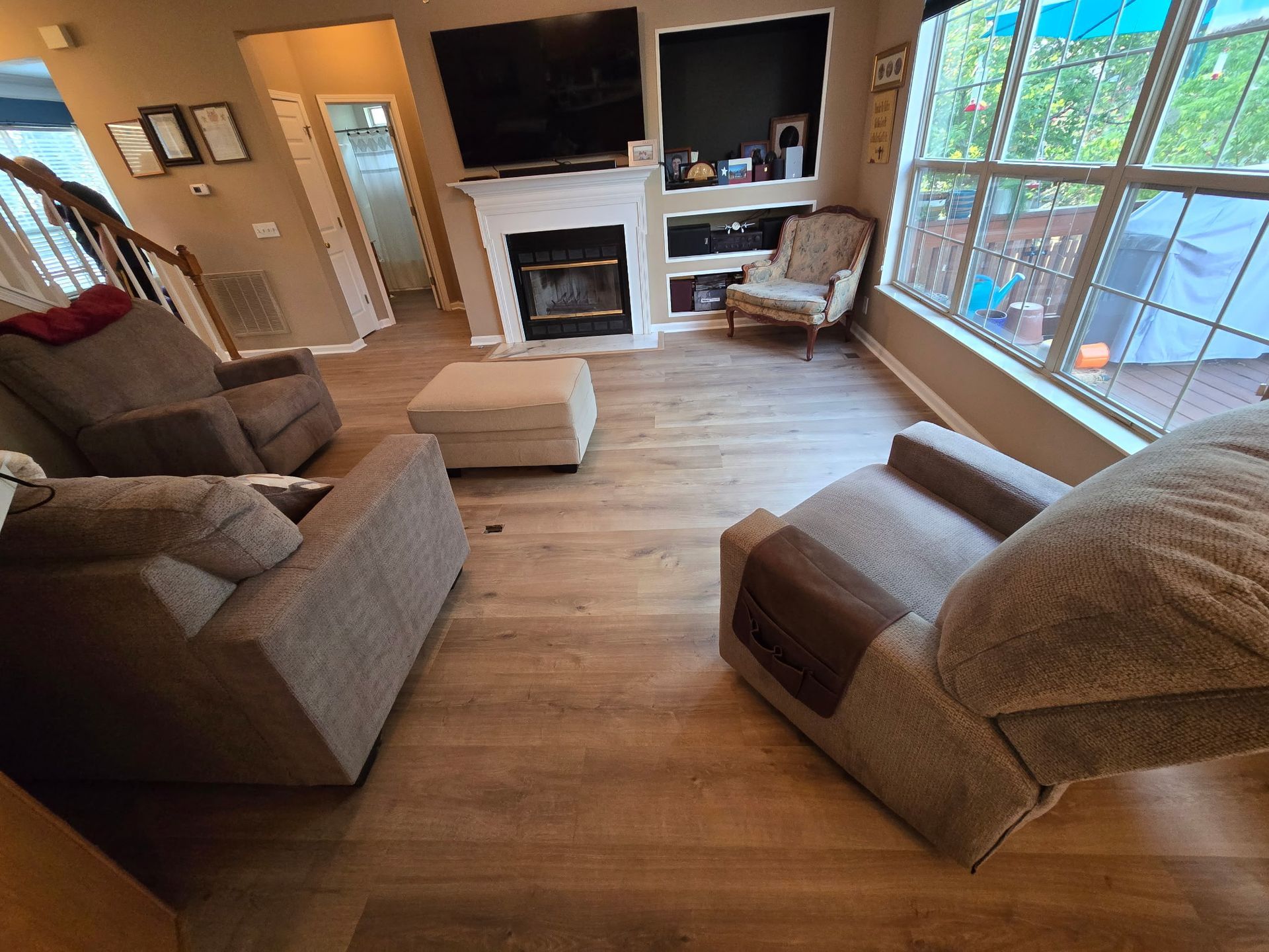 Living room with brown recliners, fireplace, and large windows with outdoor view.