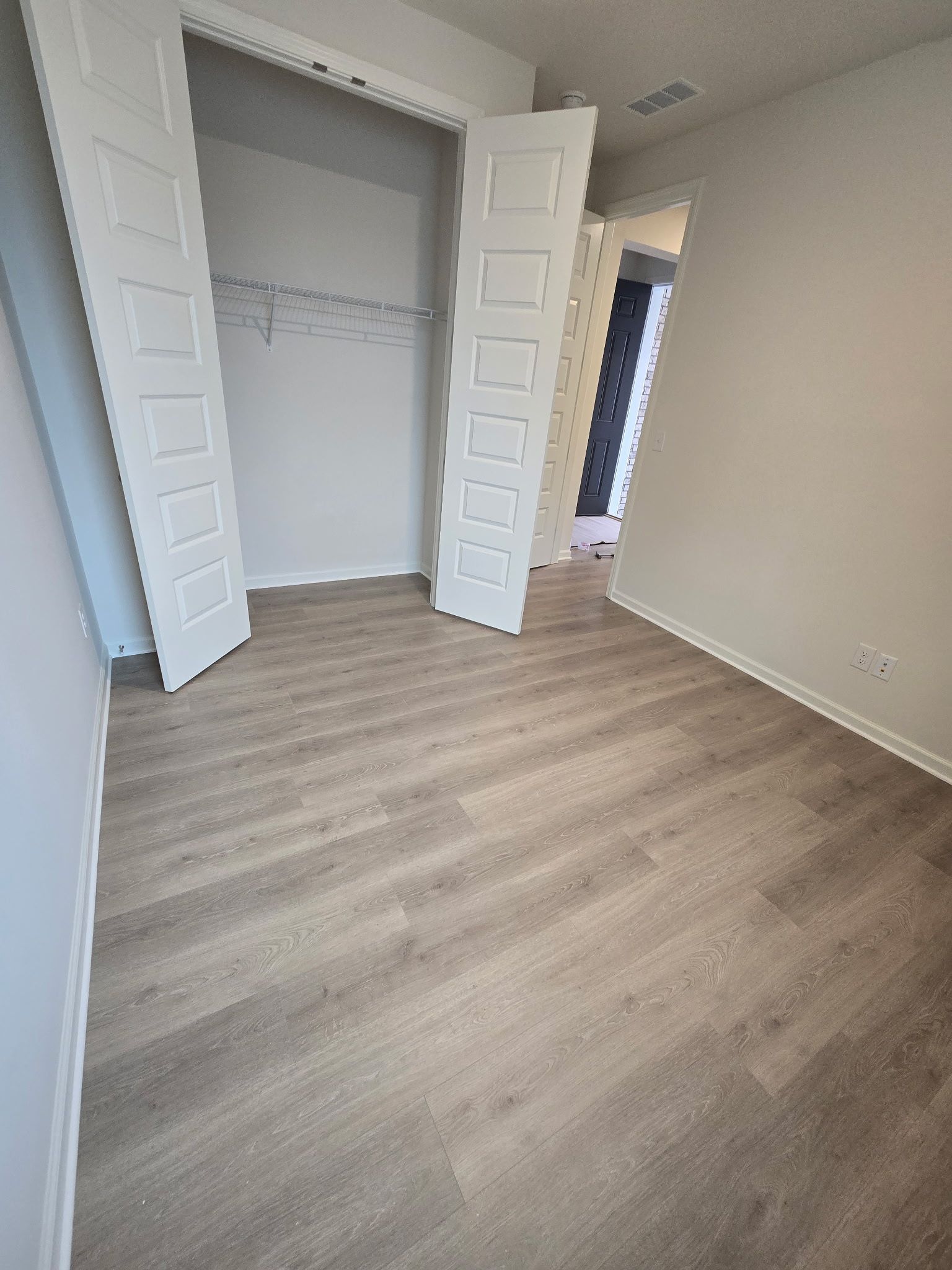 Empty room with closet and light gray flooring. White closet doors.