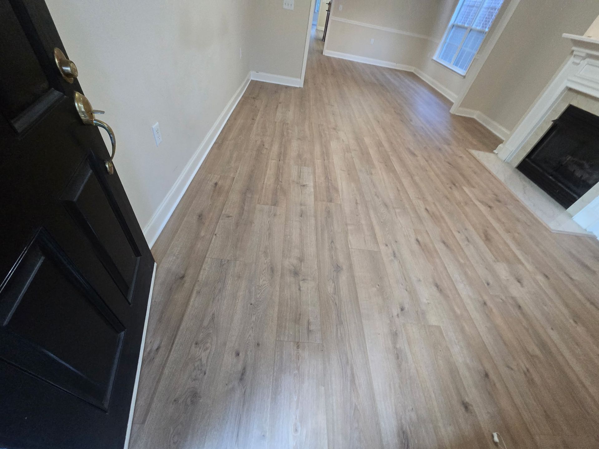 Interior view of a room with wood-look flooring, light gray walls, and a fireplace.
