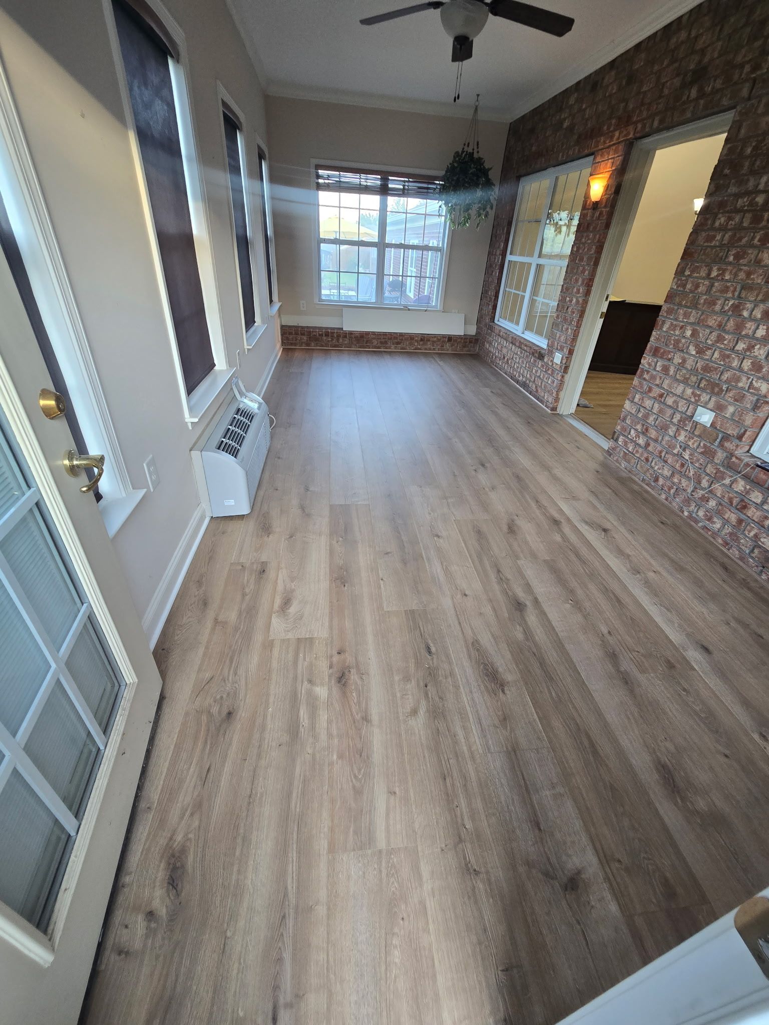 A room with wood-like floors, windows, and brick-patterned walls.