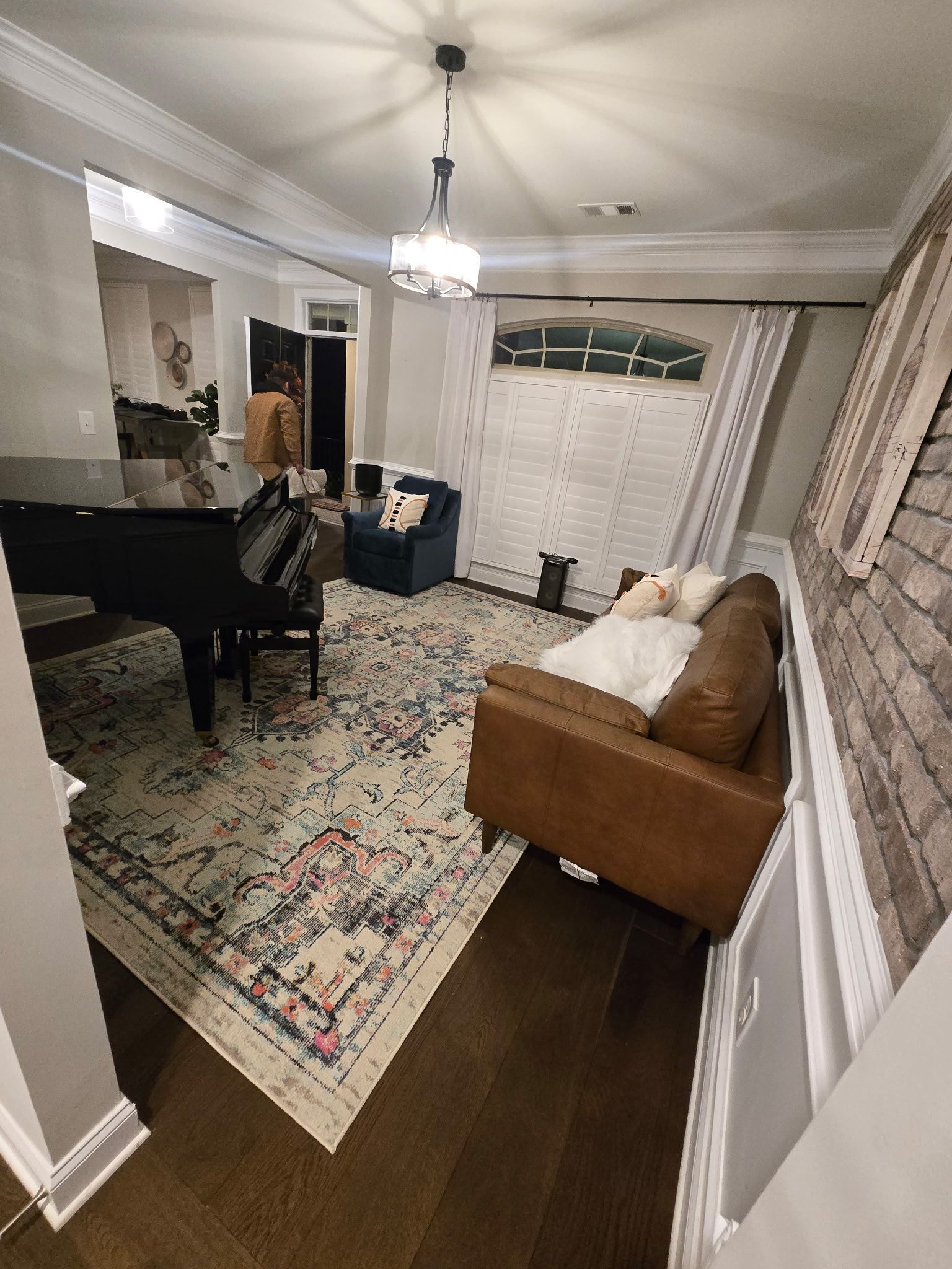Elegant living room with grand piano, patterned rug, sofa, and chandelier