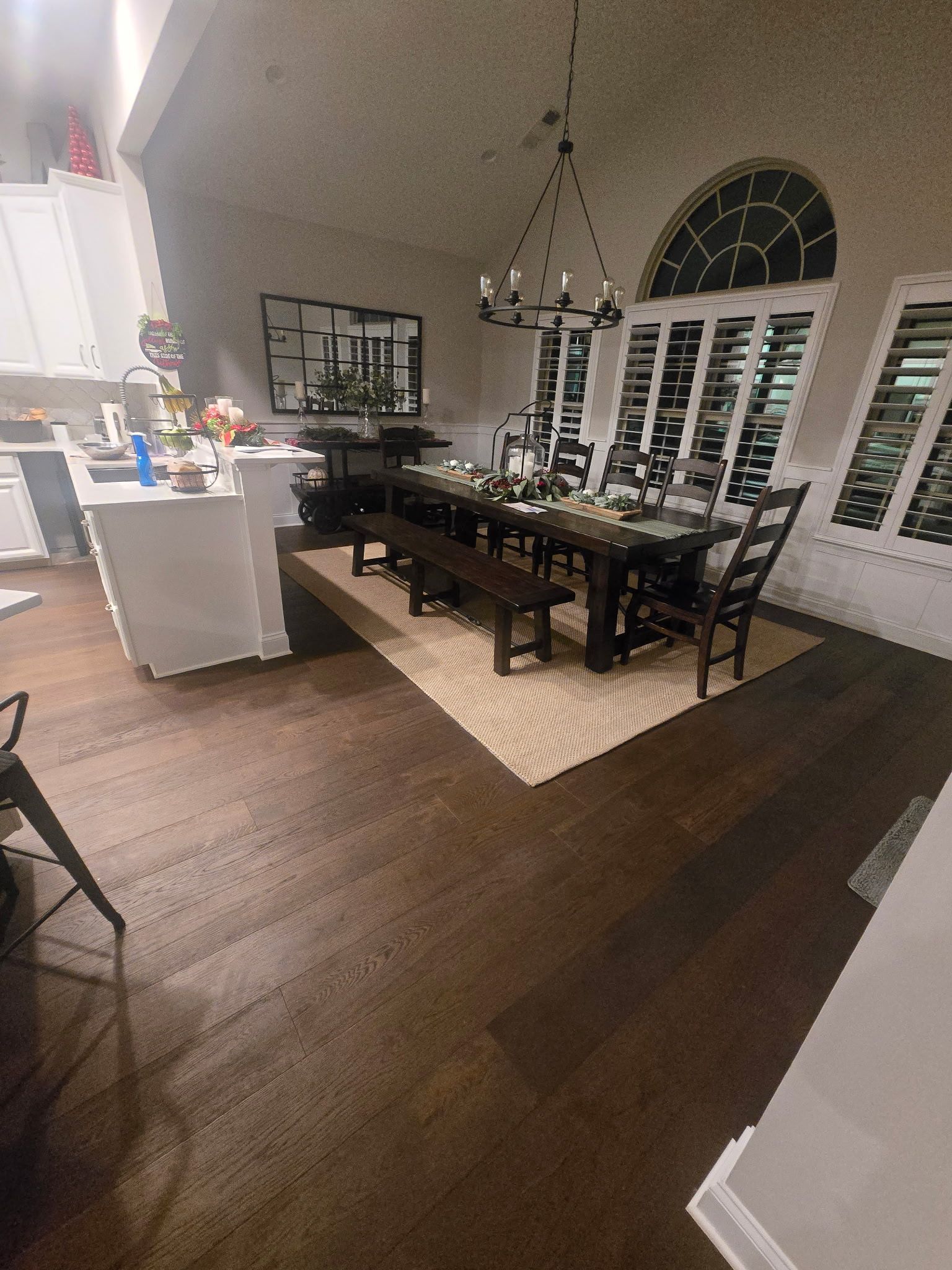 Elegant dining room with dark wood table, black chairs, chandelier, and arched window shutters