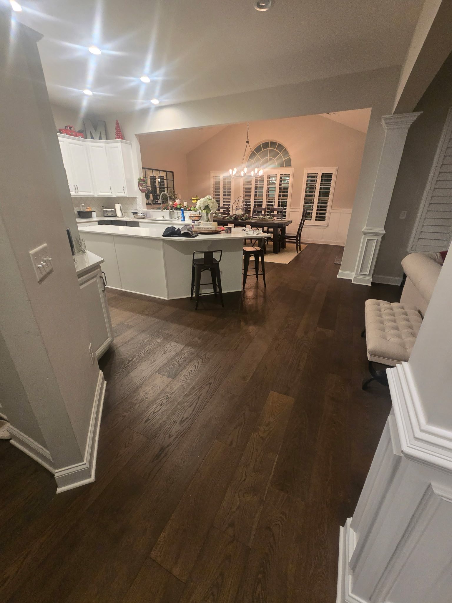 Open-concept kitchen and dining area with white cabinets, dark wood floors, and a central island.