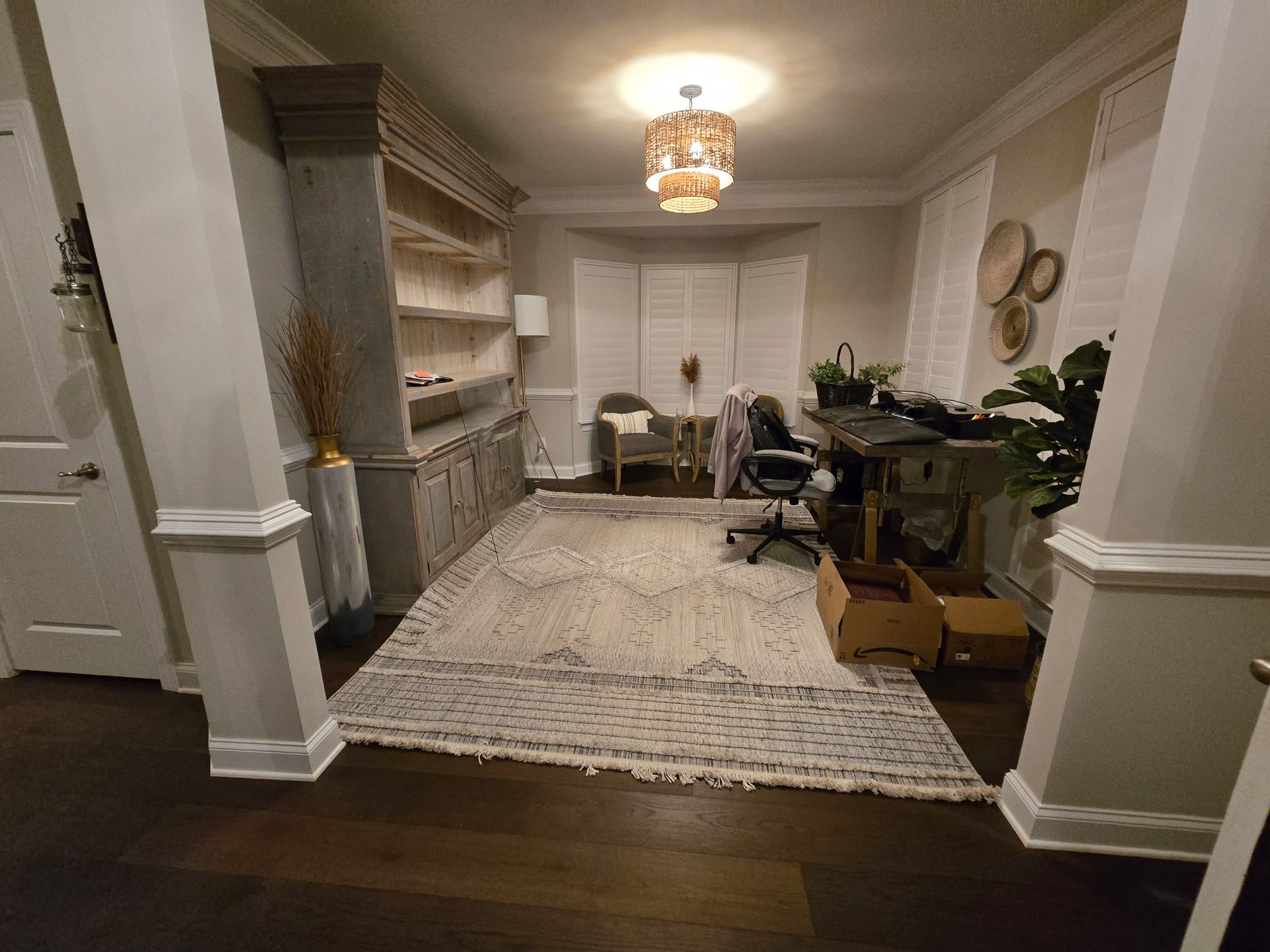Elegant home office with built-in shelves, desk, chairs, rug, and chandelier