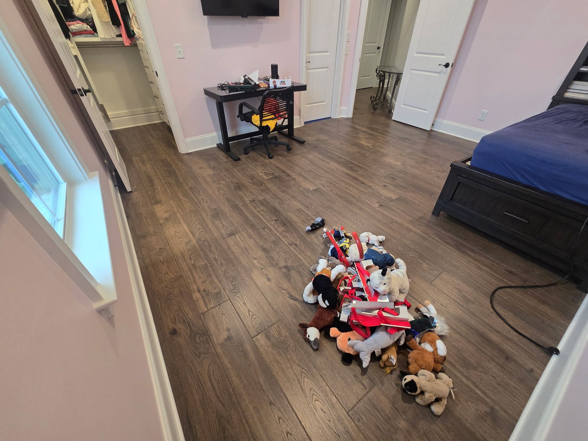 Bedroom with scattered stuffed animals on the floor, near a bed and open closet door.