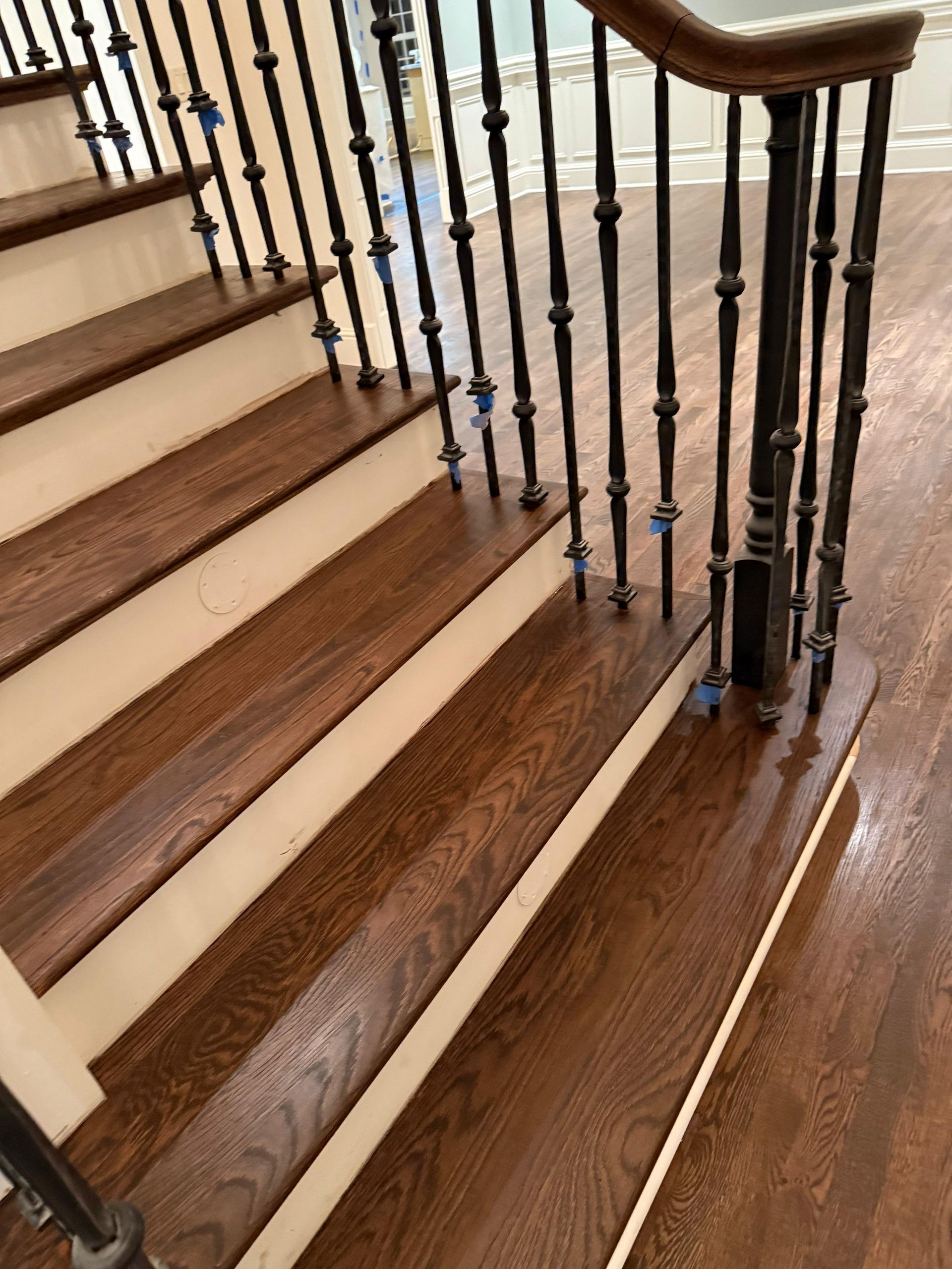 Wooden staircase with white risers and black wrought-iron railing in a home interior
