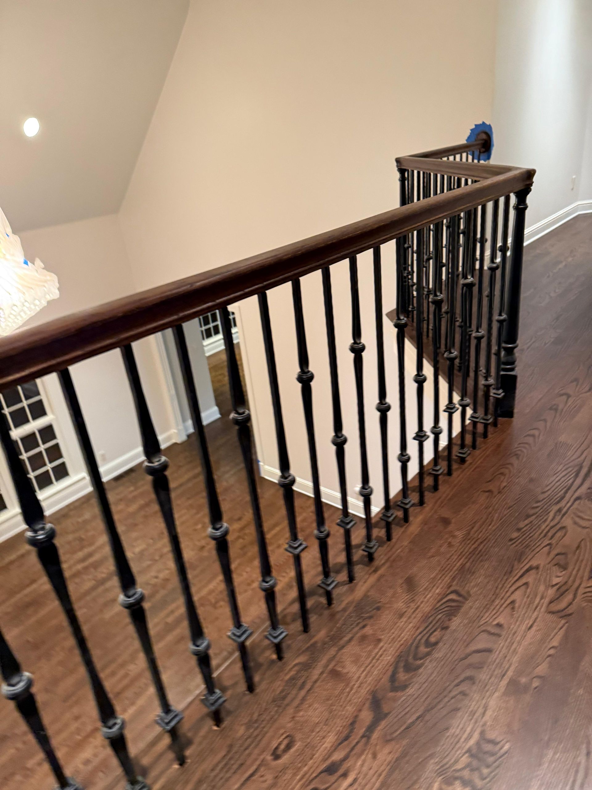 Staircase landing with dark wood banister and black balusters overlooking a lower floor and white railing