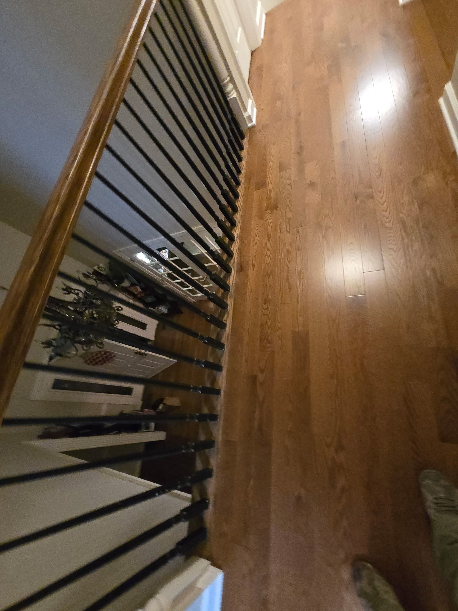 Stair railing beside a polished hardwood floor and hallway.