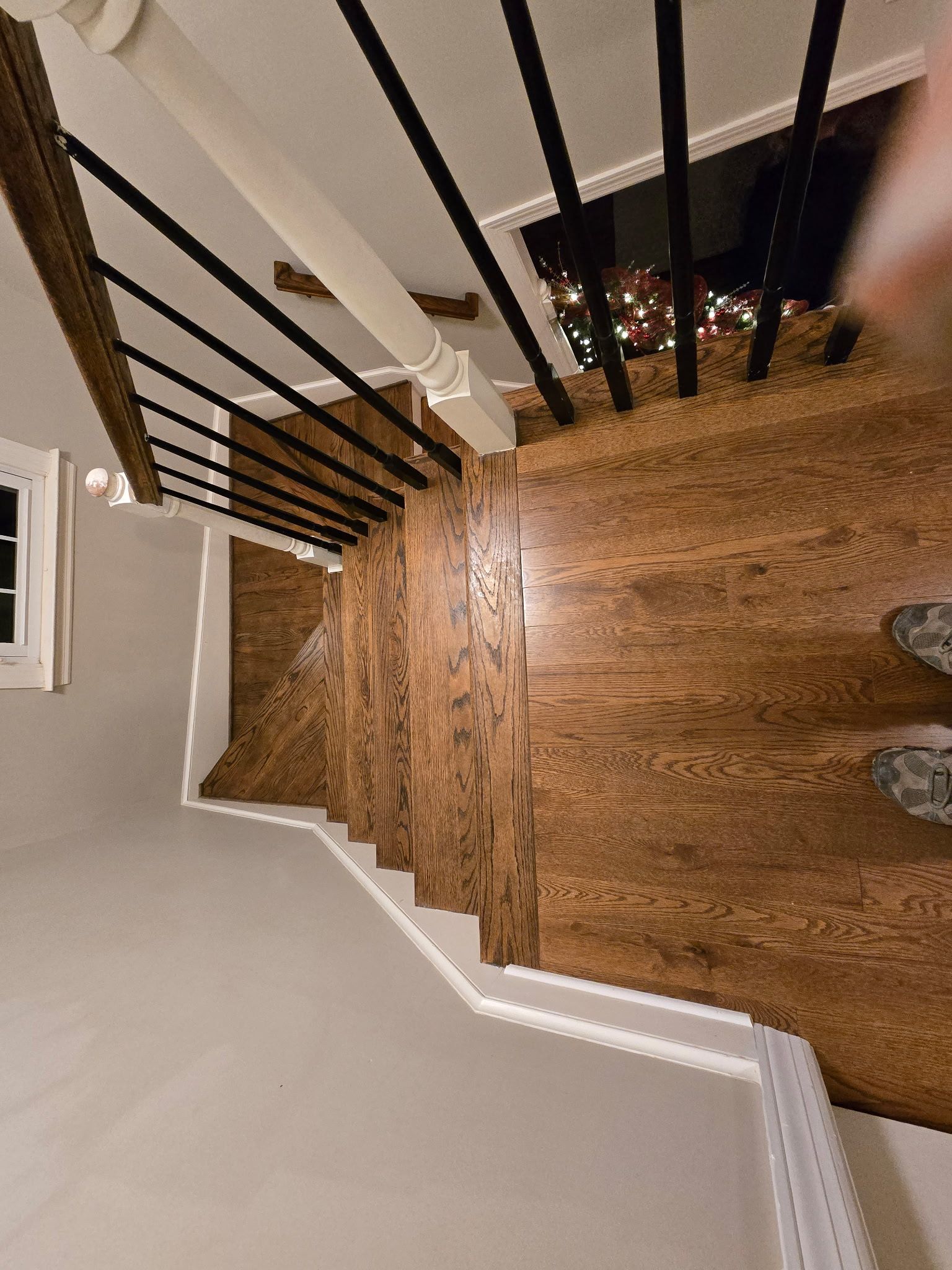 Staircase with wood steps and black railings viewed from above, inside a home