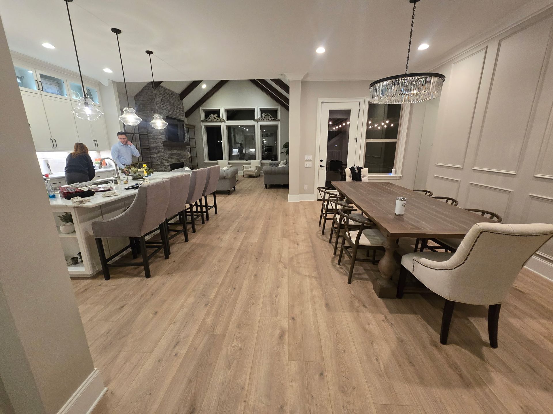 Elegant dining room with set tables, upholstered chairs, and a buffet counter under bright pendant lights.