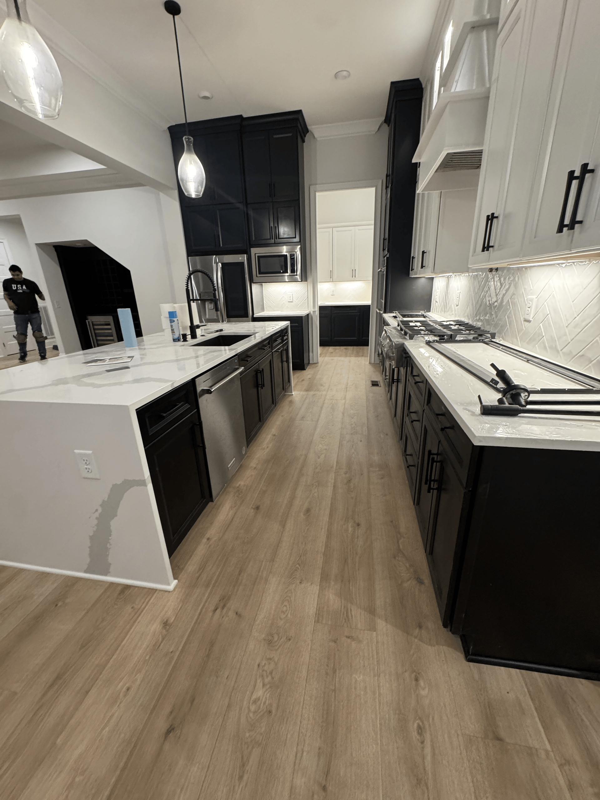 Modern kitchen with black and white cabinets, light wood floors, and a long island.