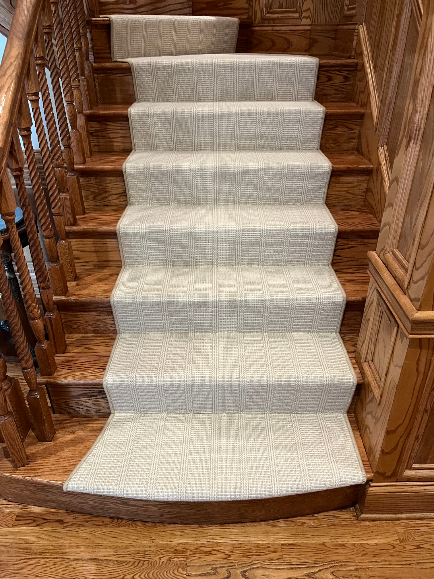 Carpeted staircase with a light runner and wooden banisters in a home interior