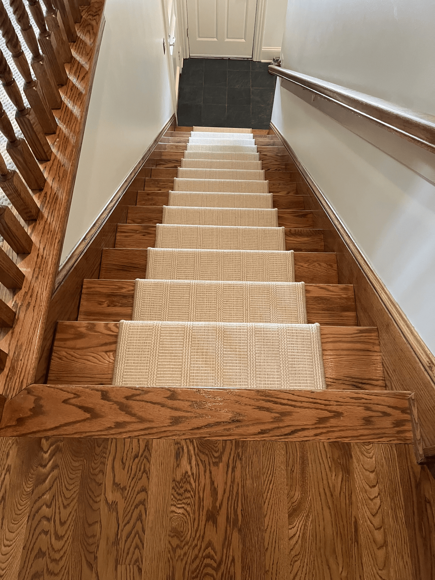Carpeted wooden staircase with a handrail, leading up to a closed white door.