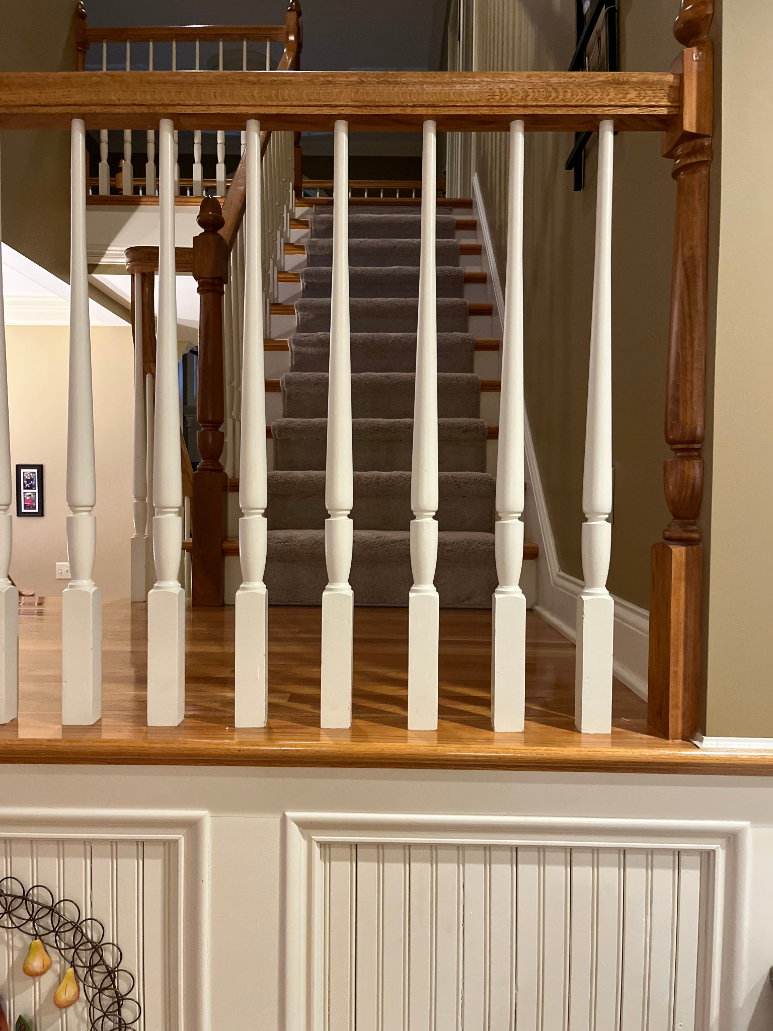 Staircase behind white balusters and wooden handrail in a home interior