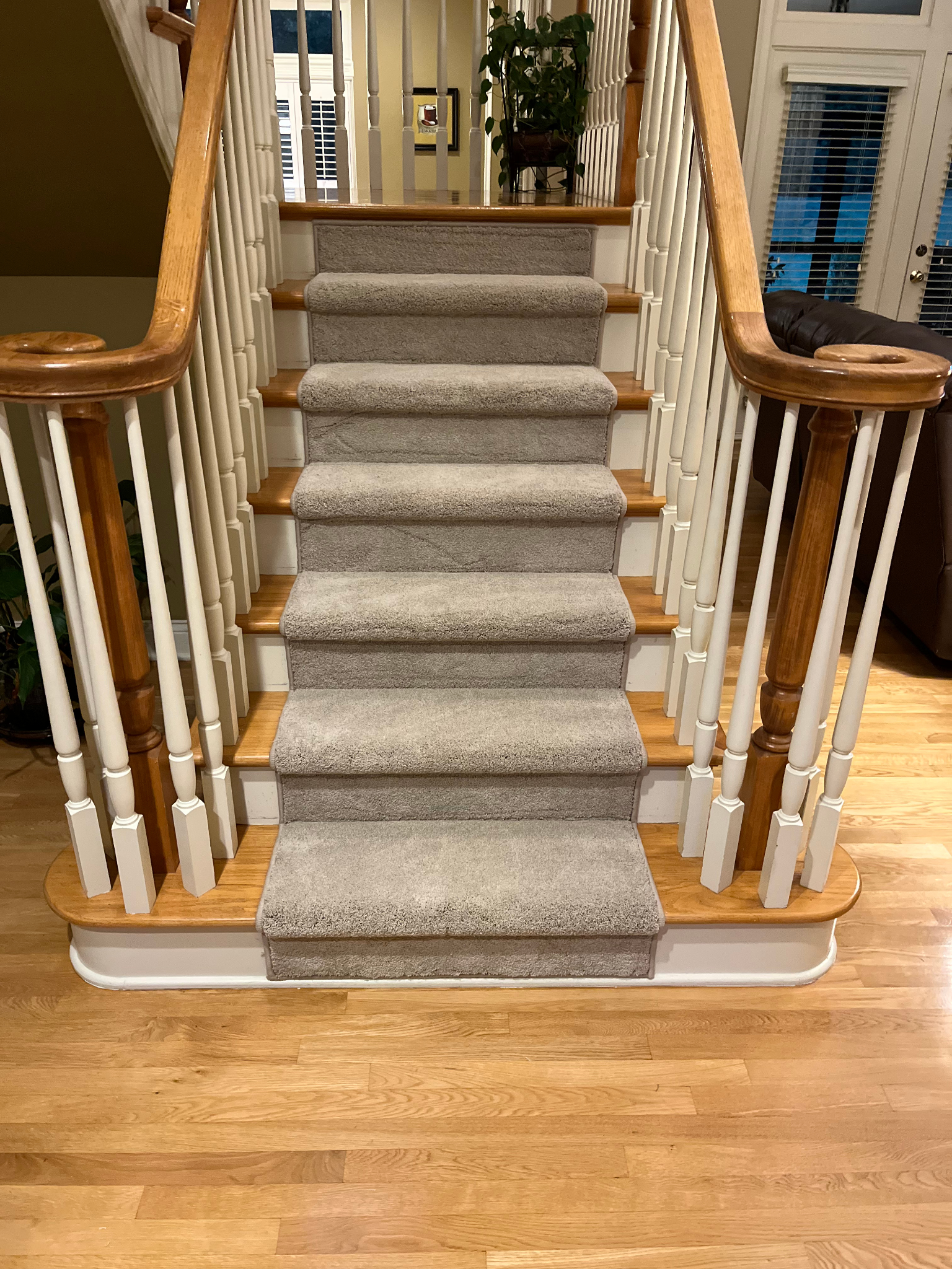 Carpeted staircase with wooden railings leading to an upper hallway in a home.