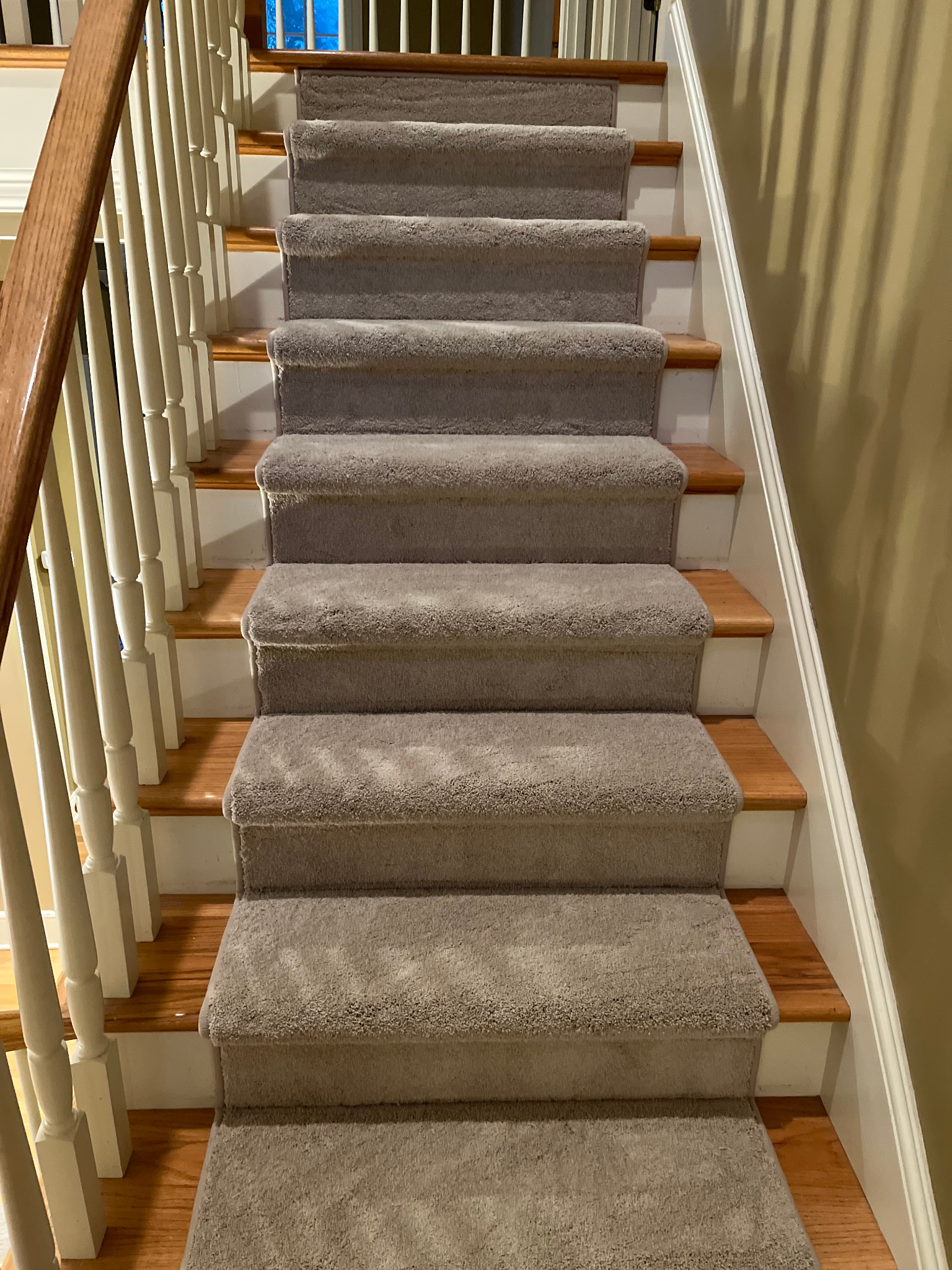 Carpeted staircase with wooden banisters and striped wallpaper in a home interior