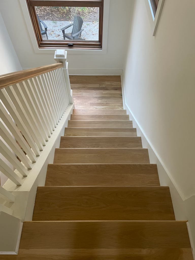 Staircase with white railing and wooden steps leading up to a windowed landing.