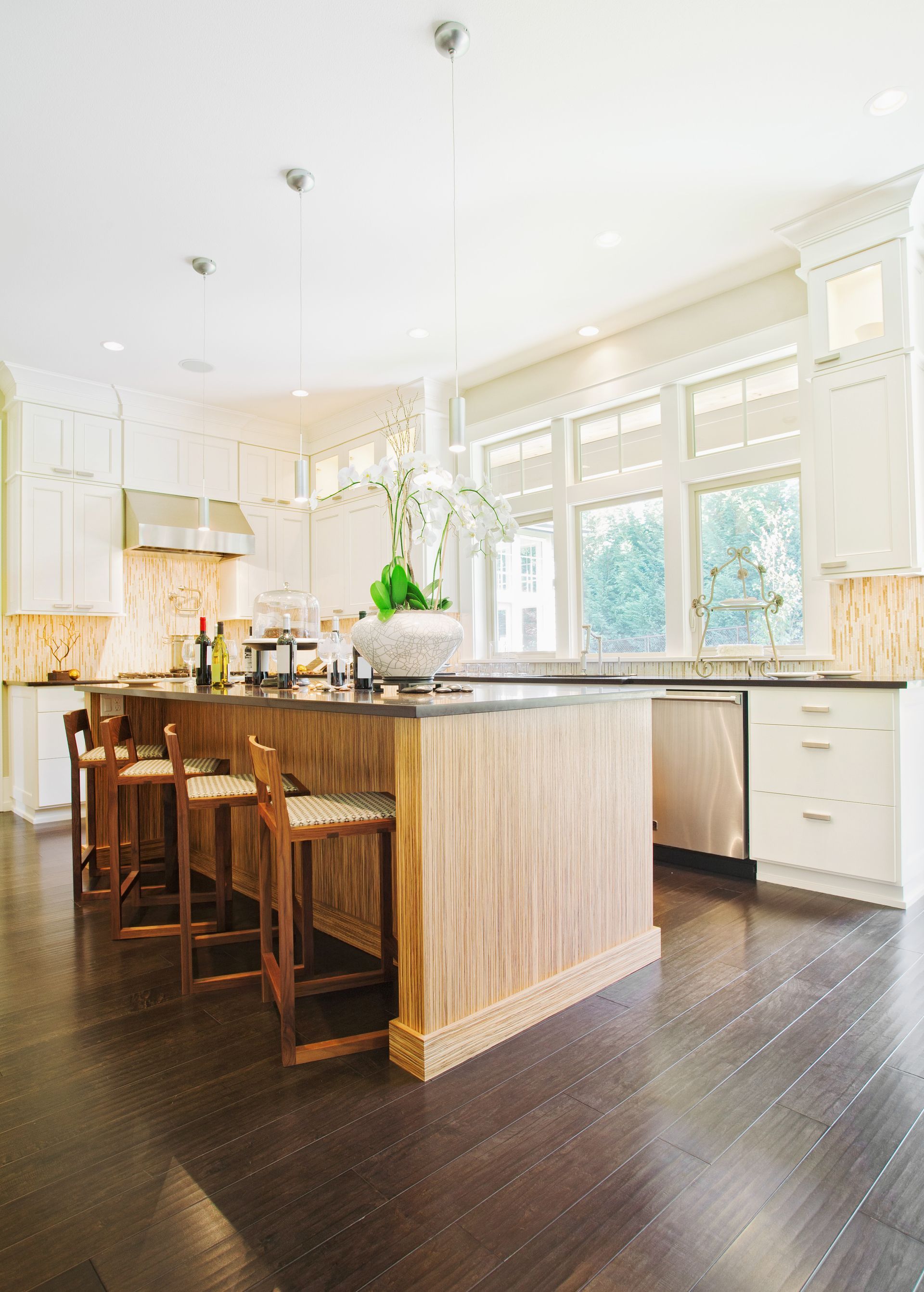 Modern kitchen with wooden island, stainless steel appliances, and white cabinets; hardwood floors.