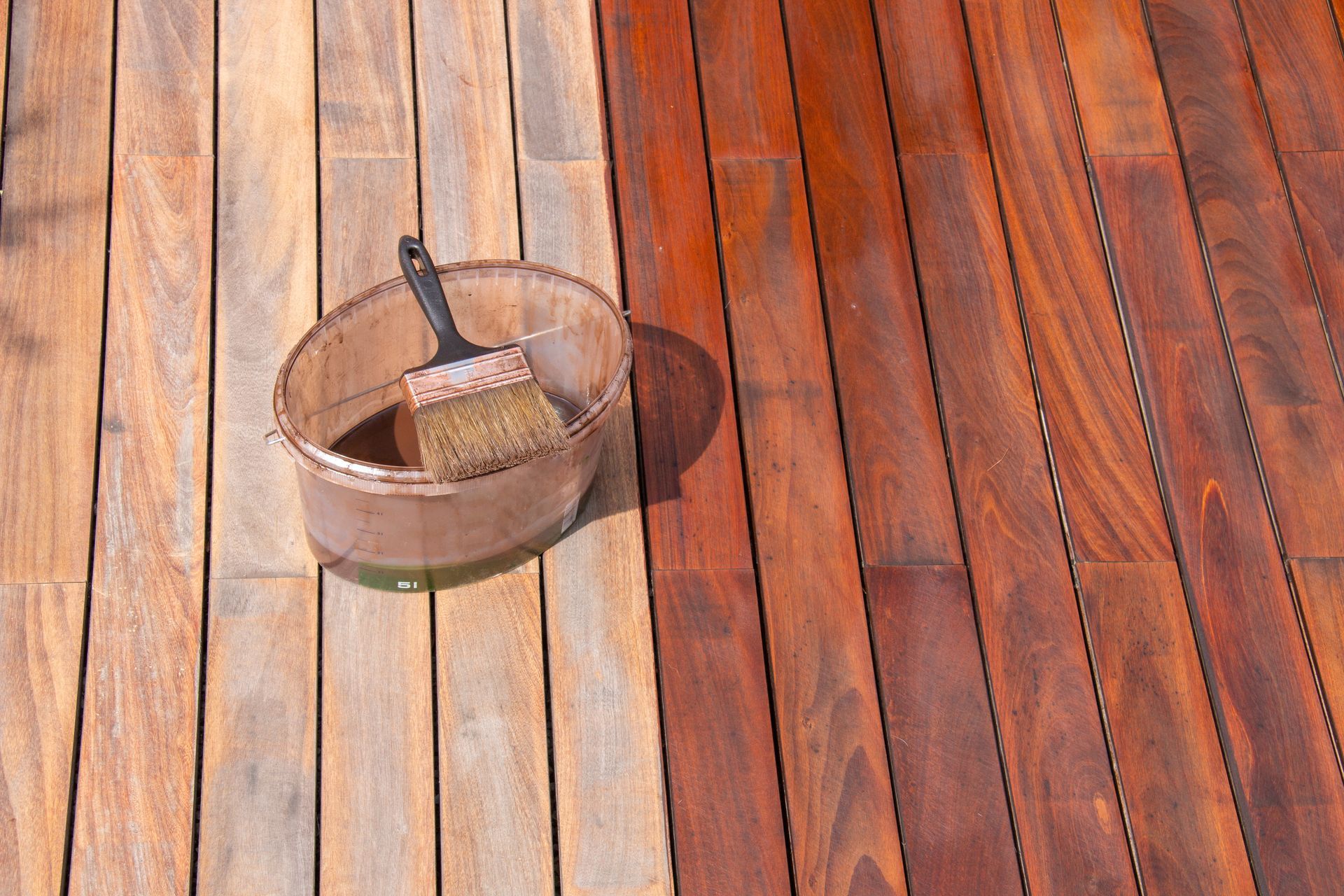 Metal bucket and brush on a sunlit wooden deck