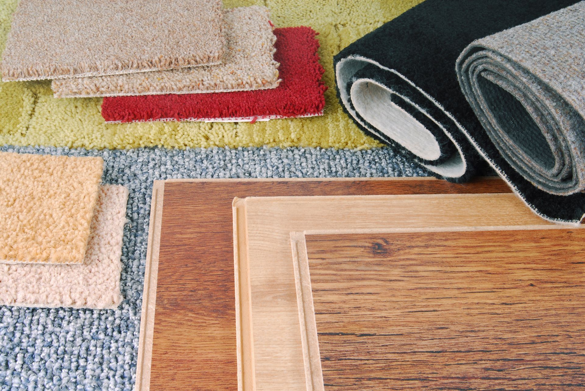 Assortment of flooring samples: carpets in various colors and textures, and wood planks.