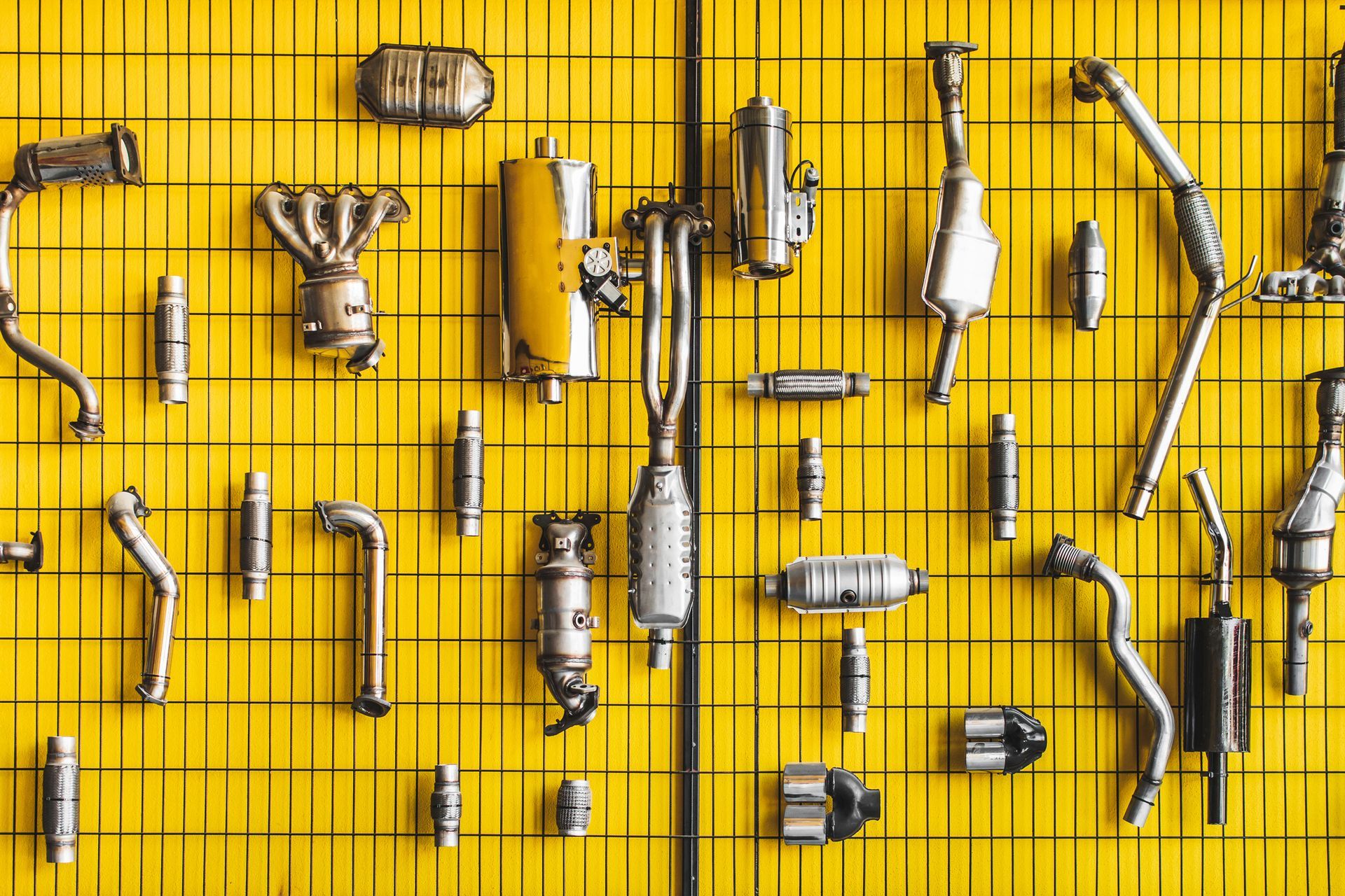 Various car exhaust parts displayed on a yellow grid wall.