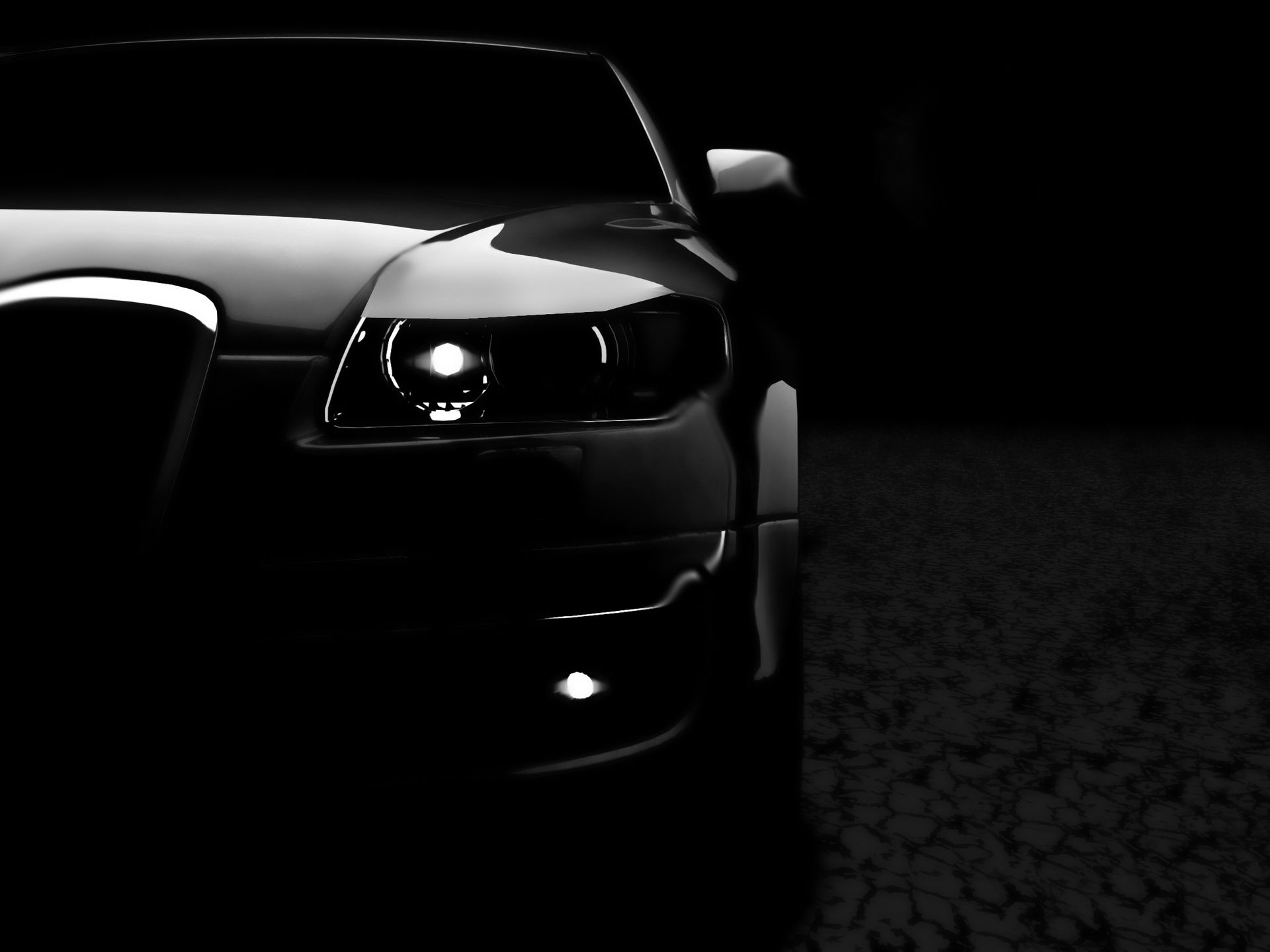 Black and white photo of a car front. One headlight and fog light are lit in the dark.