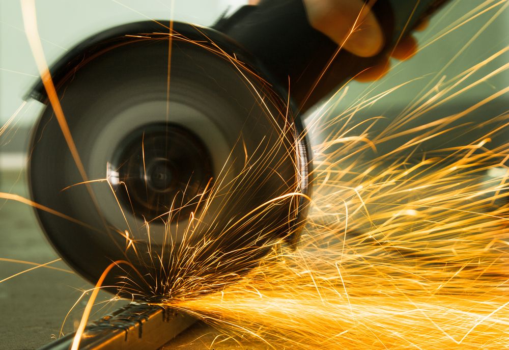 A Person is Using a Grinder to Cut a Piece of Metal — Top End Steel Supplies Darwin In NT