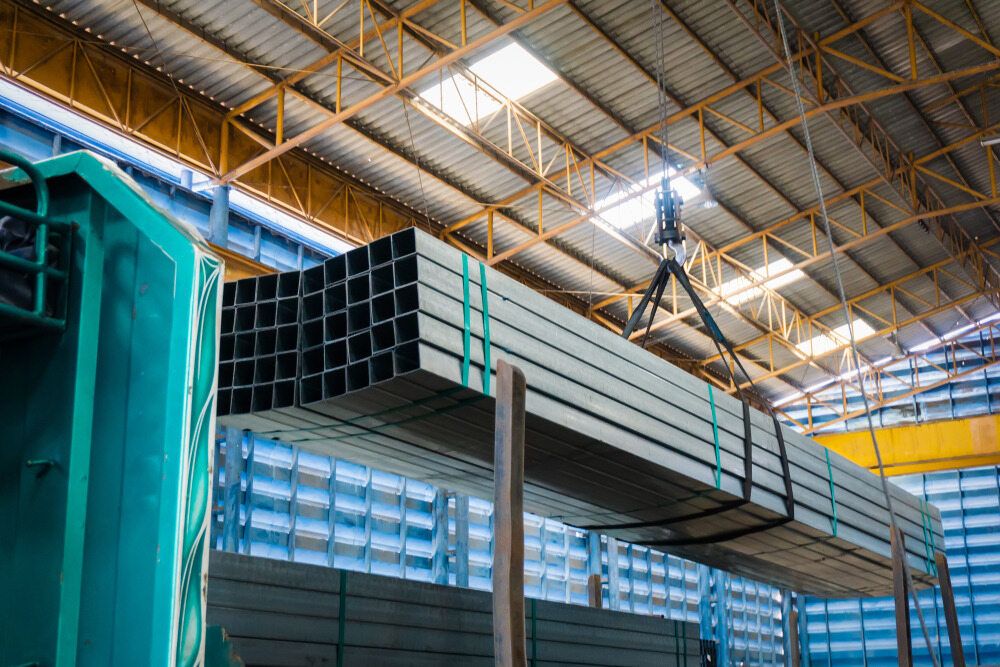 A Crane is Lifting a Stack of Metal Pipes in a Warehouse — Top End Steel Supplies Darwin In Tennant Creek, NT