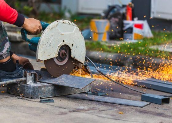 A Man is Cutting a Piece of Metal With a Circular Saw — Top End Steel Supplies Darwin In Pinelands, NT
