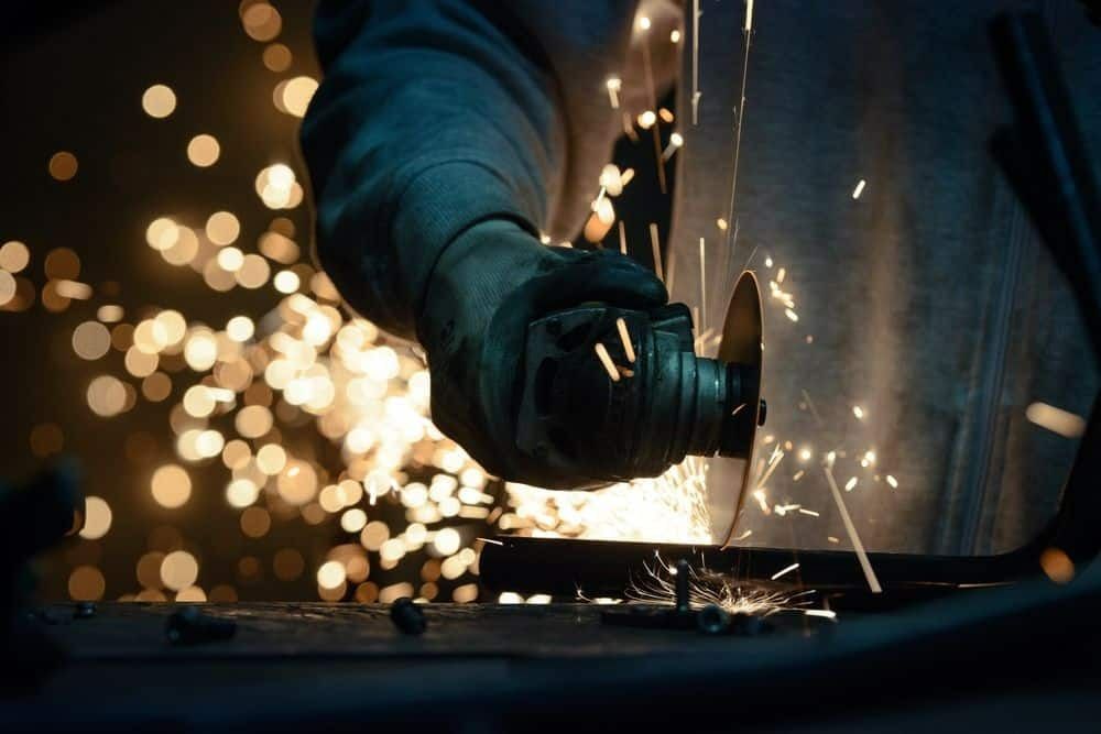 A Person is Cutting a Piece of Metal With a Grinder — Top End Steel Supplies Darwin In Humpty Doo, NT