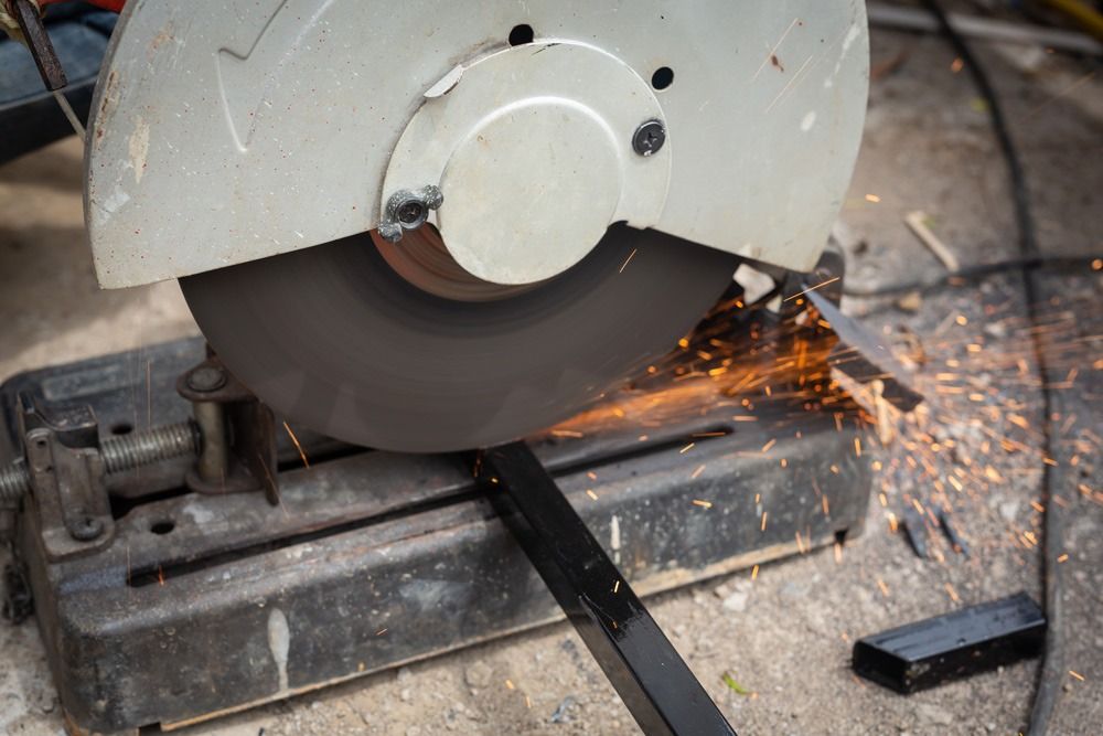 A Person is Cutting a Piece of Metal With a Circular Saw — Top End Steel Supplies Darwin In Katherine, NT