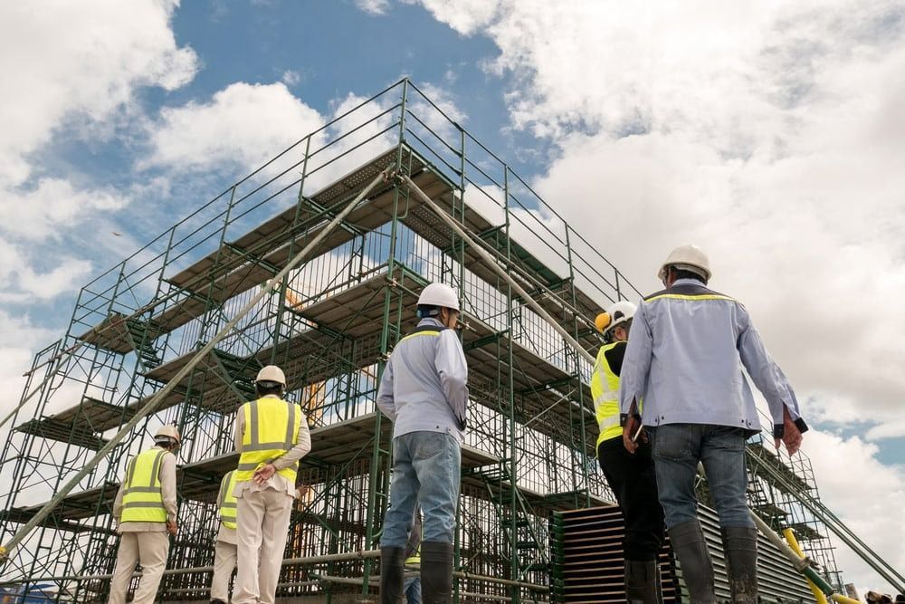 A Group of Construction Workers Are Standing in Front of a Building — Top End Steel Supplies Darwin In Pinelands, NT