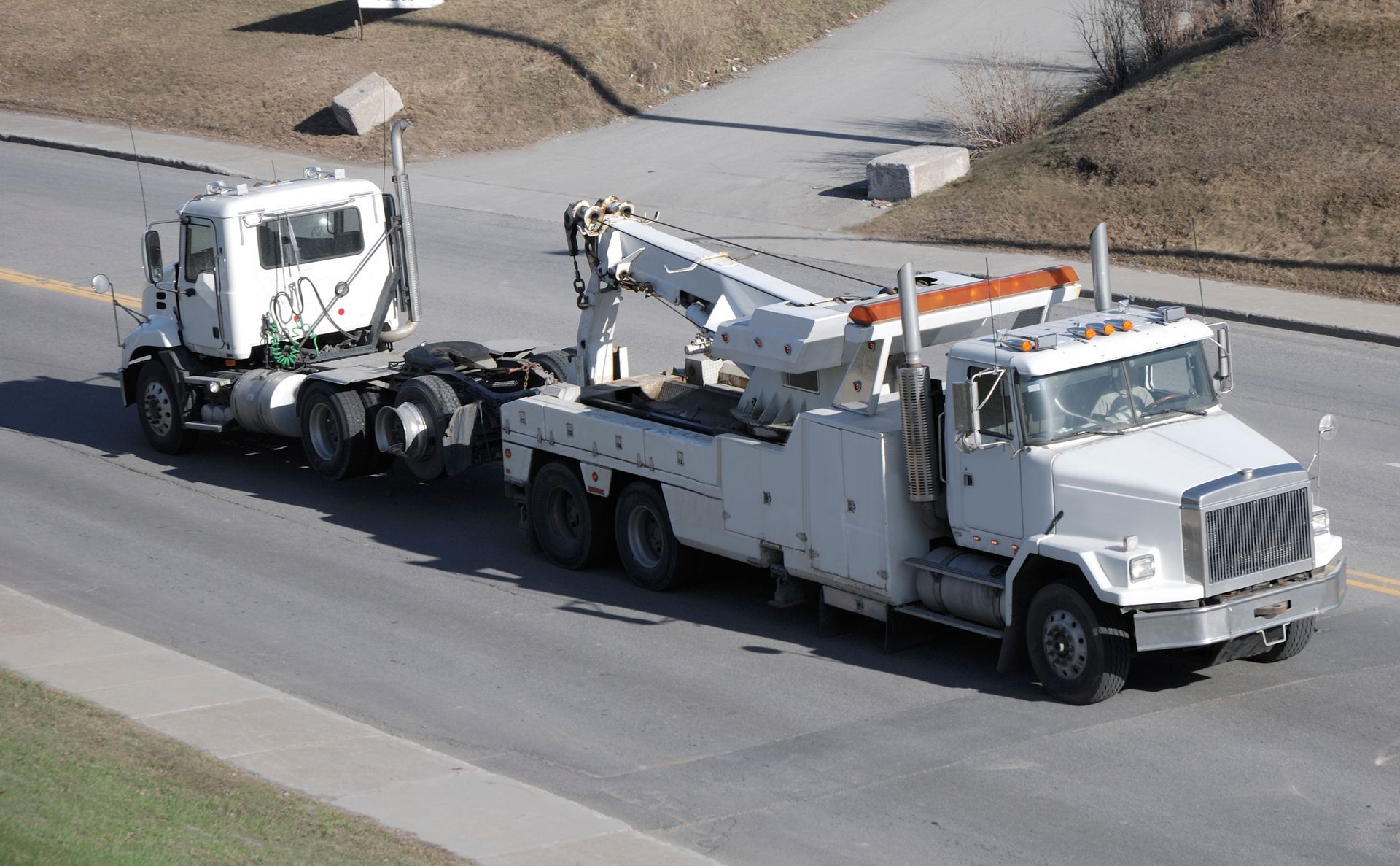 Big semi-truck tow by heavy tow truck.