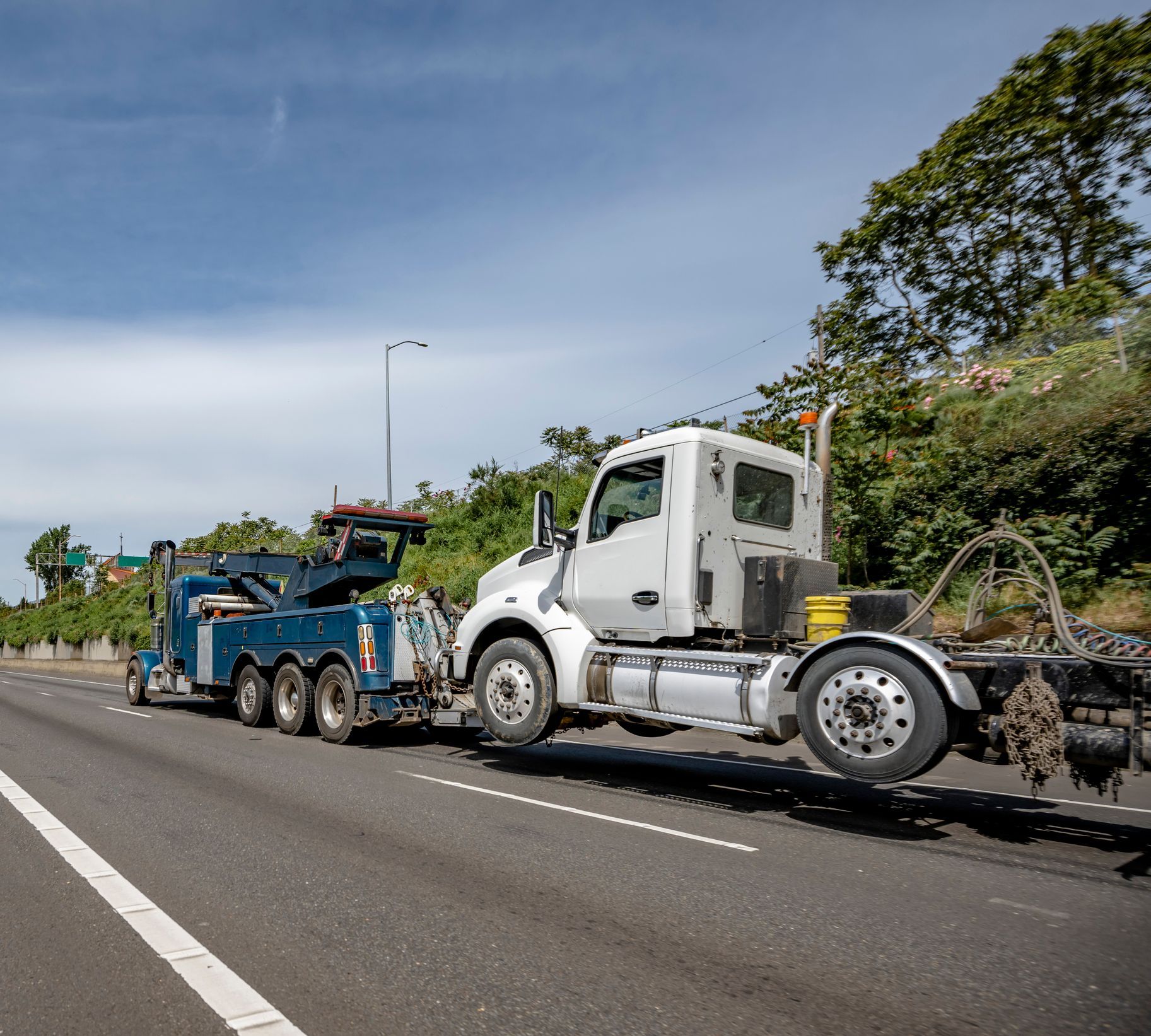 Powerful mobile helper heavy duty blue big rig towing semi-truck tractor.